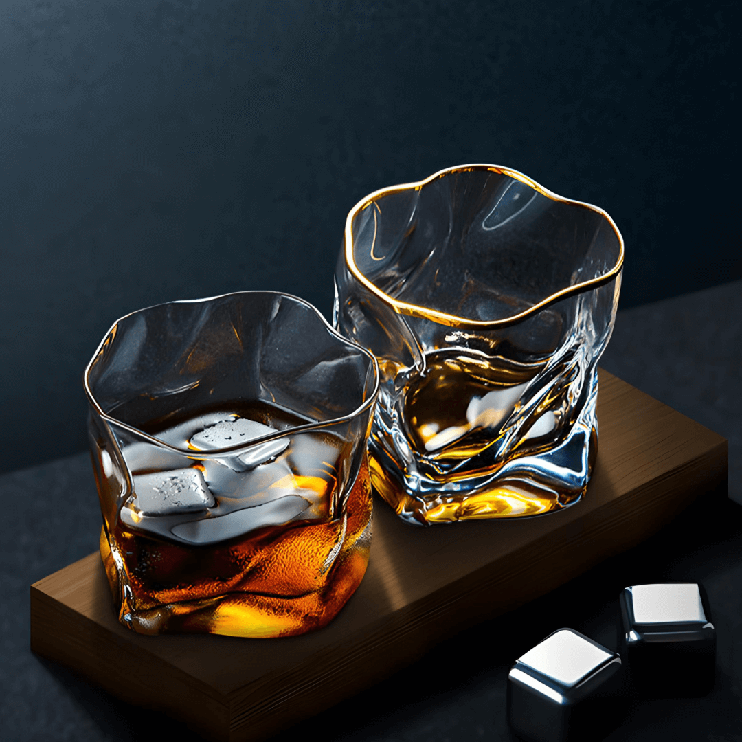 Two gold-rimmed Hoshi crystal whisky glasses with textured sides and amber whisky swirling on a wooden base.