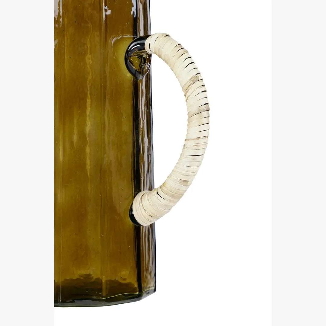Hammered brown glass water pitcher with a beige woven handle attached by black rings.