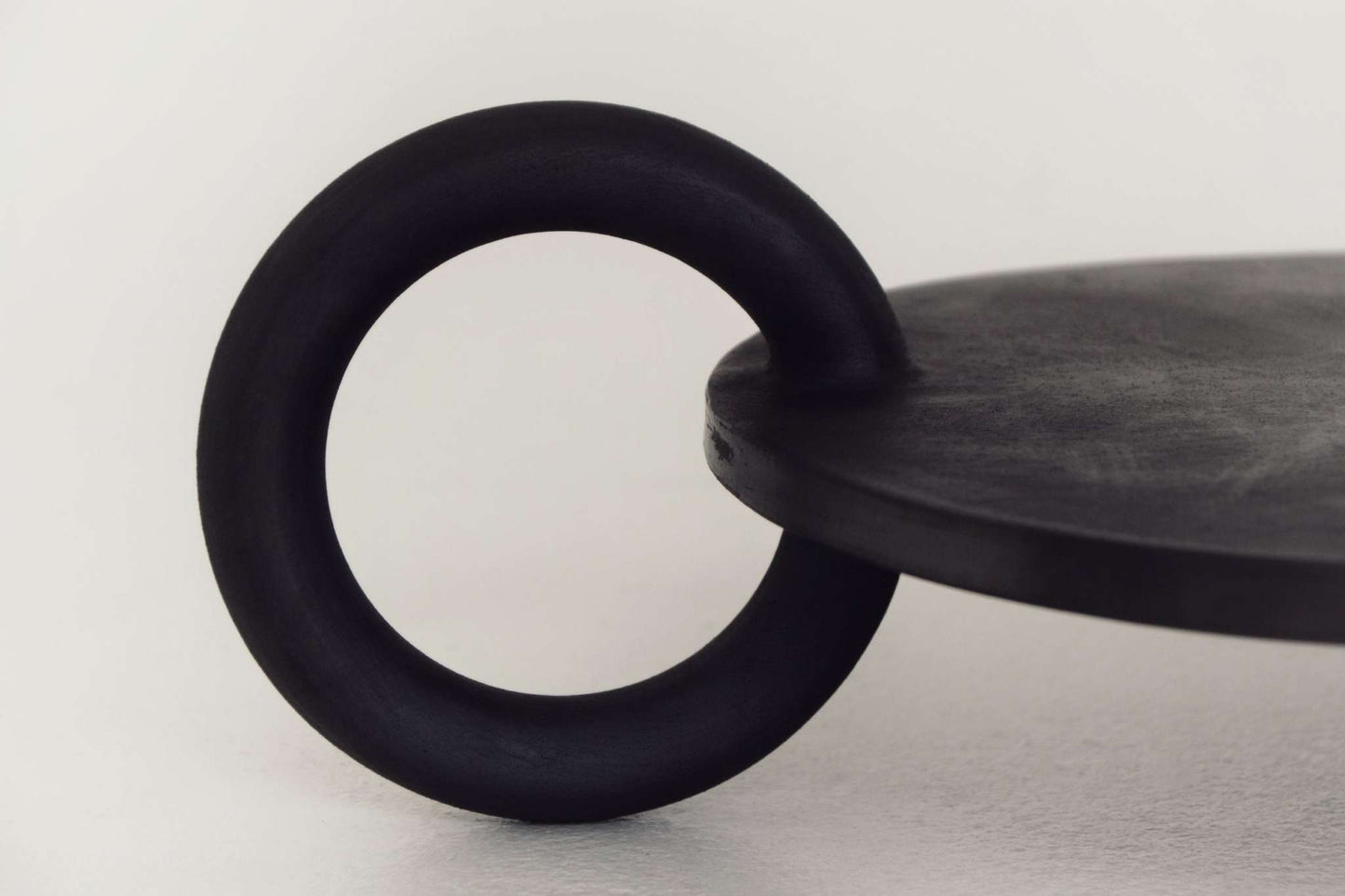 Large serving platter with a black circular ring handle, matte finish, from Guculia Trinity collection.