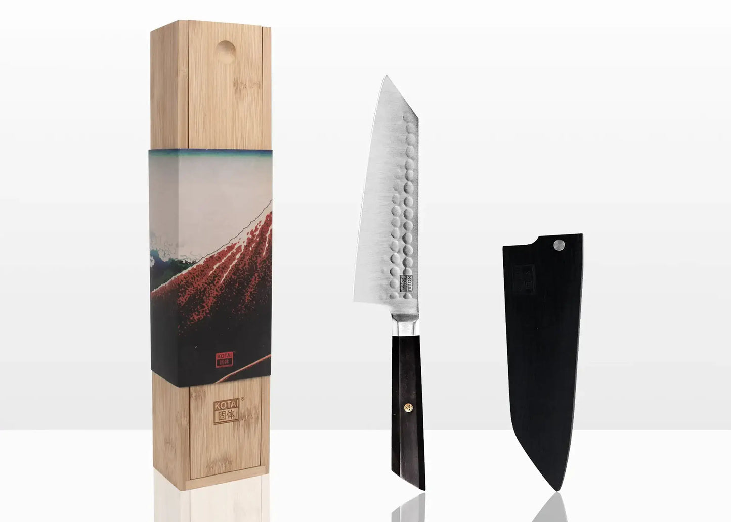 KOTAI Bunka Santoku kitchen knife with hammered blade, black handle, sheath, and wooden presentation box.