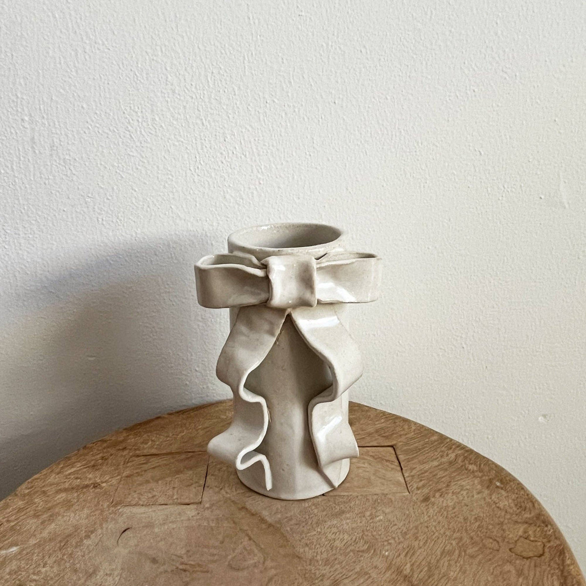 Handmade white glazed stoneware vase featuring a sculpted ribbon bow detail for a whimsical, elegant centerpiece.