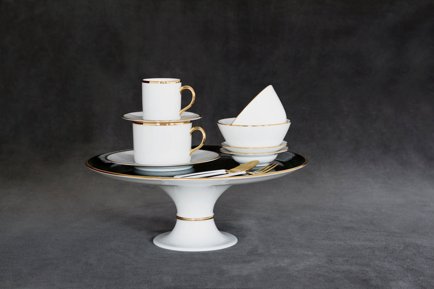 Lush Forest Footed Cake Stand in white porcelain with 24k gold trim, stacked cups and bowls.