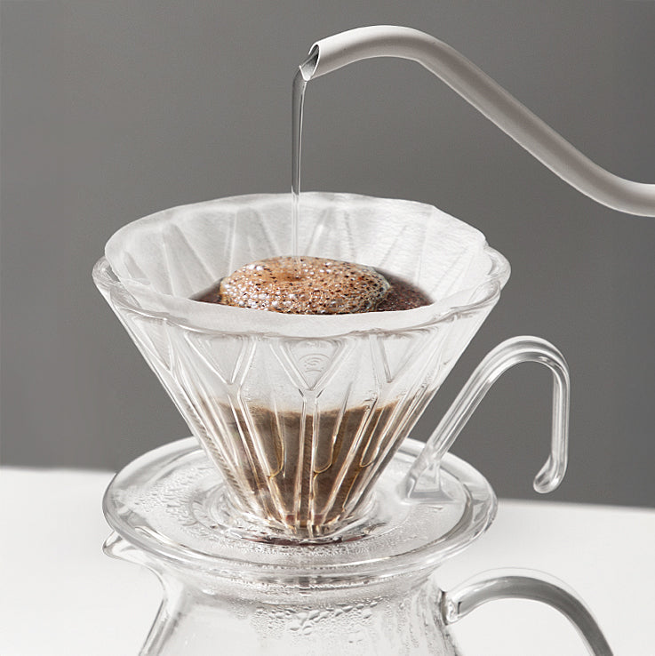 Diamond Pattern Prisma Pour Over Dripper in clear PCTG with rhombic filter cup atop a glass carafe.