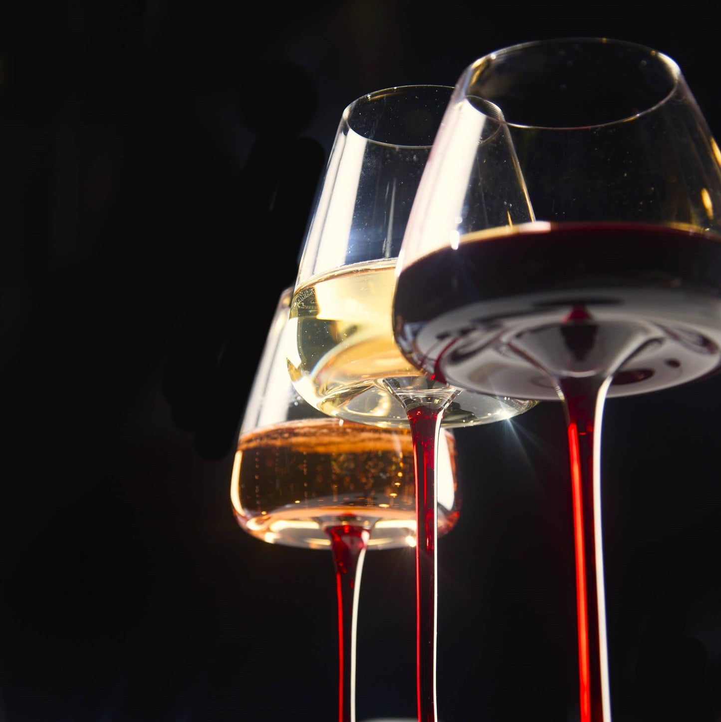 Three Extra Large Concave Wine Glasses, 24oz capacity, filled with red and white wine, elegant tall stemware.