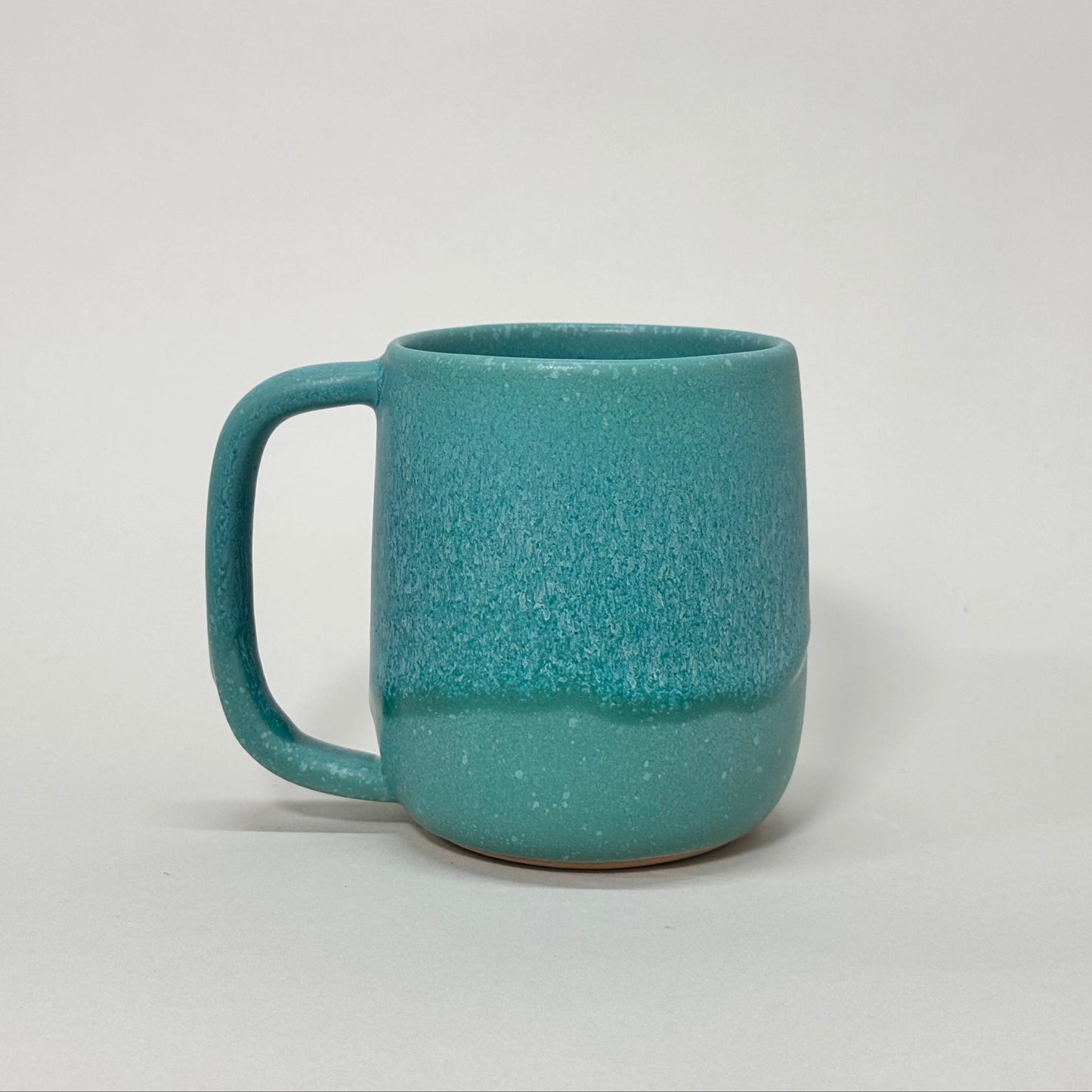 The Standard Mug: teal speckled ceramic mug with a sturdy handle and 12 oz capacity.
