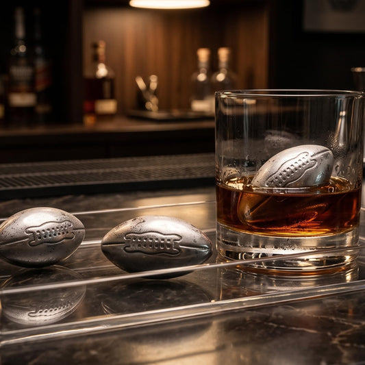 Stainless steel football whiskey stones chilling amber spirits in a glass without dilution. Reusable metal ice cubes for spirits.