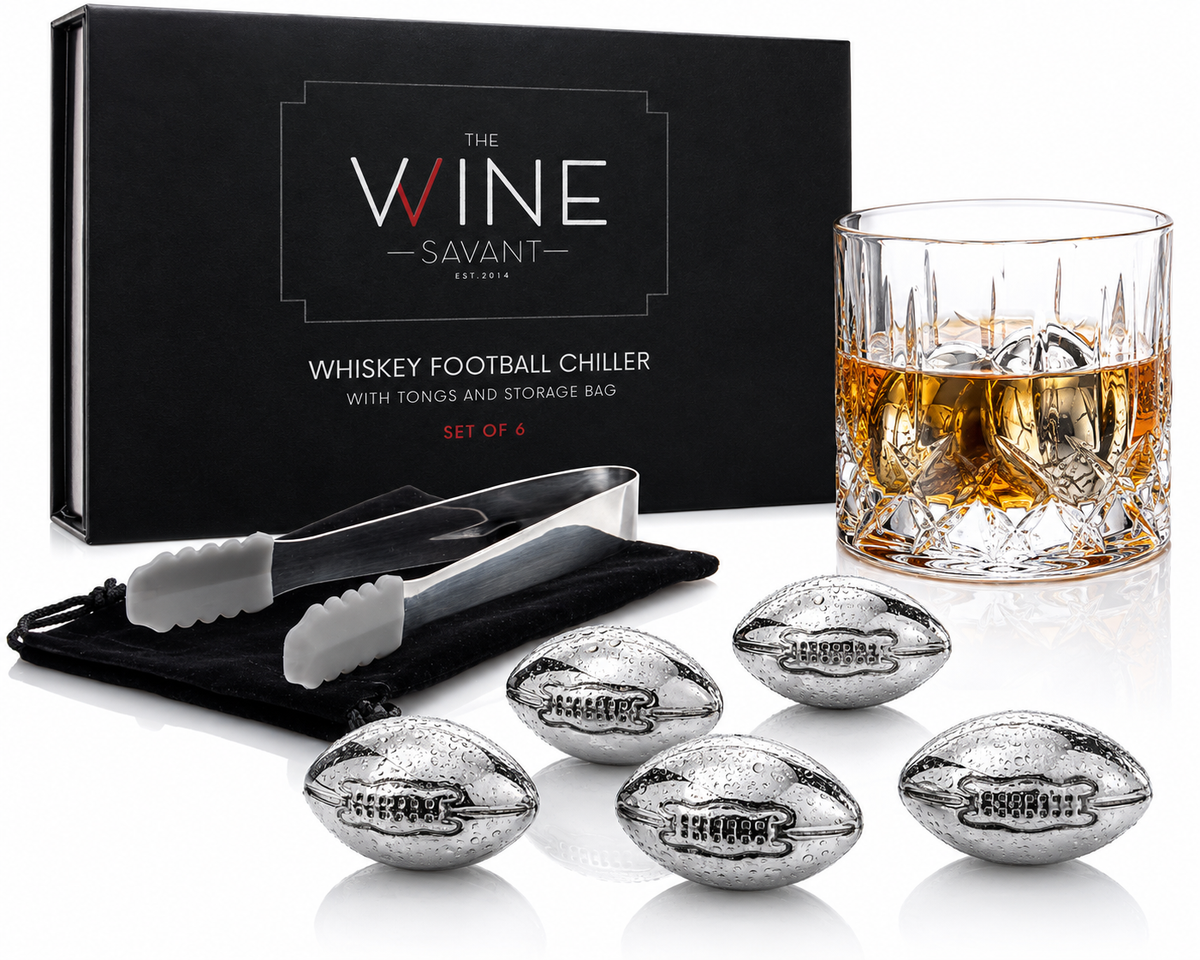 Stainless steel football whiskey stones chilling a glass of amber spirit, displayed with tongs and black storage bag against a branded box.