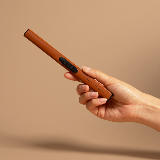 Burnt Orange Rechargeable Electric Lighter held in hand with flameless ignition for candles and fireplaces.