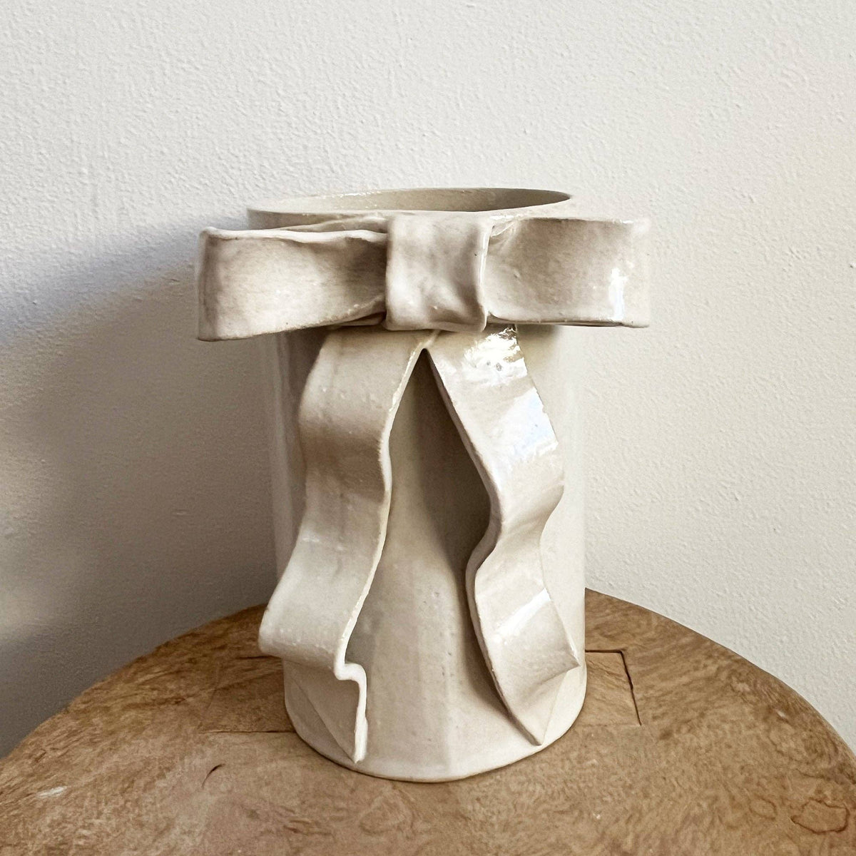Handmade satin white glazed stoneware cylindrical vase with an elegant ceramic ribbon bow detail, perfect for whimsy and timeless charm.
