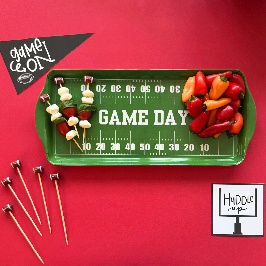 Green football field melamine tray holding appetizer skewers and peppers for game day tailgate parties.