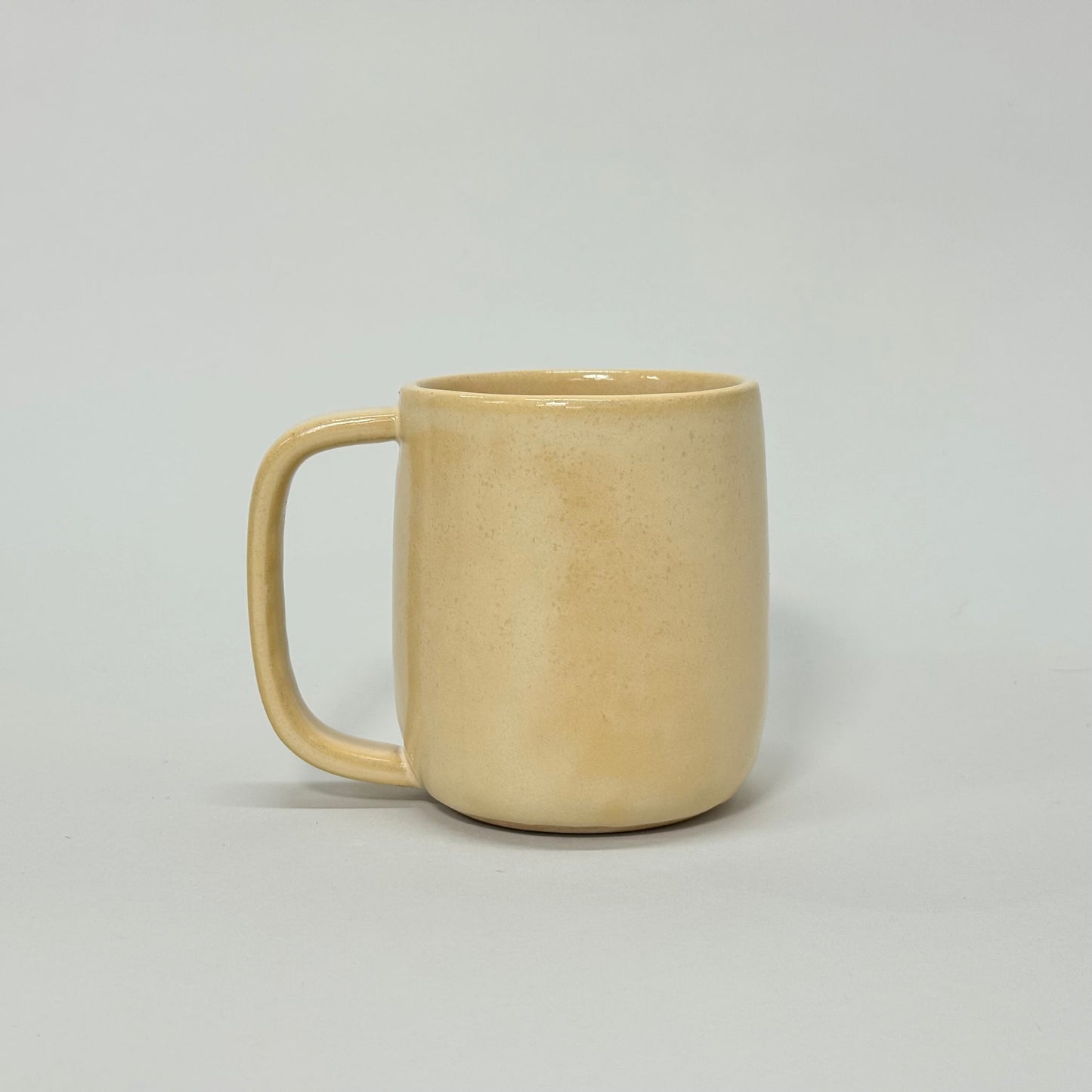 The Standard Mug: beige ceramic mug with a rounded handle, 12oz capacity for comfortable daily use.