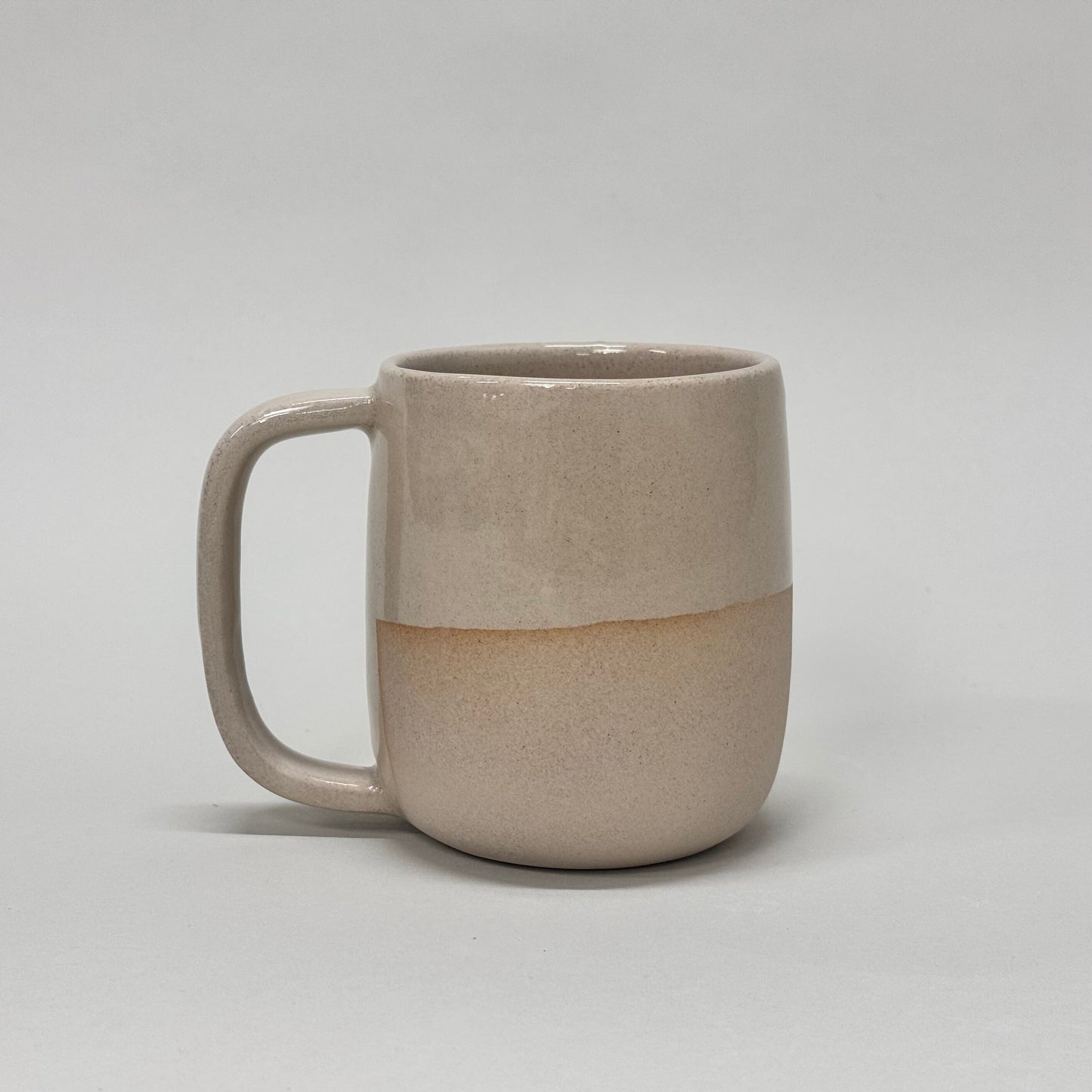 The Standard Mug: beige ceramic with a horizontal color split, comfortable handle, 12oz capacity.
