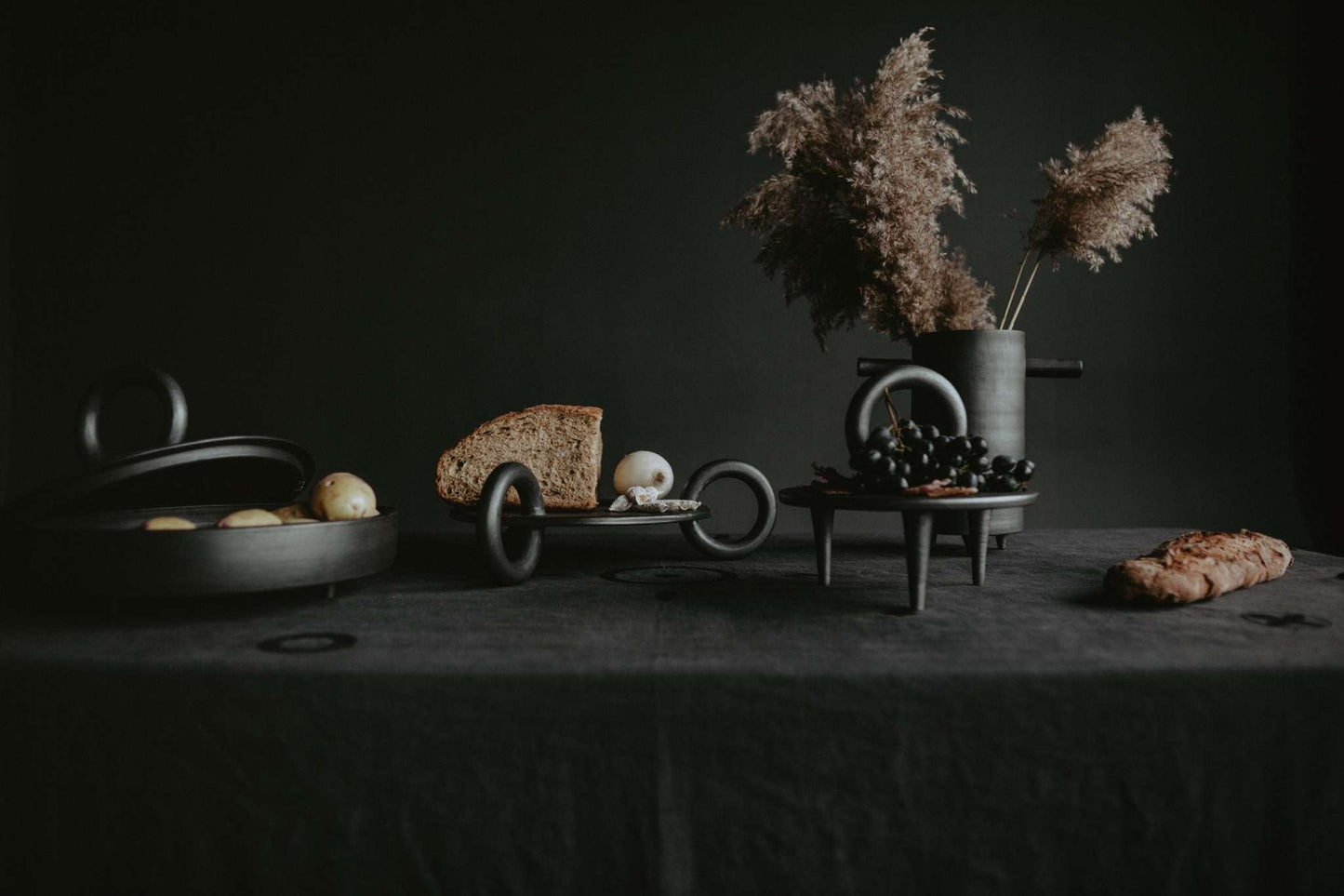Large Serving Platter Guculia. Trinity with bread, grapes, and a pampas grass vase on a dark table.