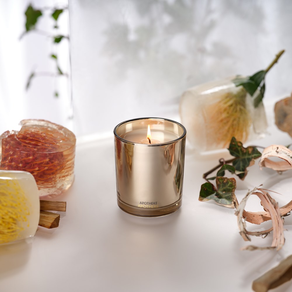 Firewood Classic Candle in gilded brown vessel with a glistening gold interior, lit wick, warm crackling bonfire aroma.