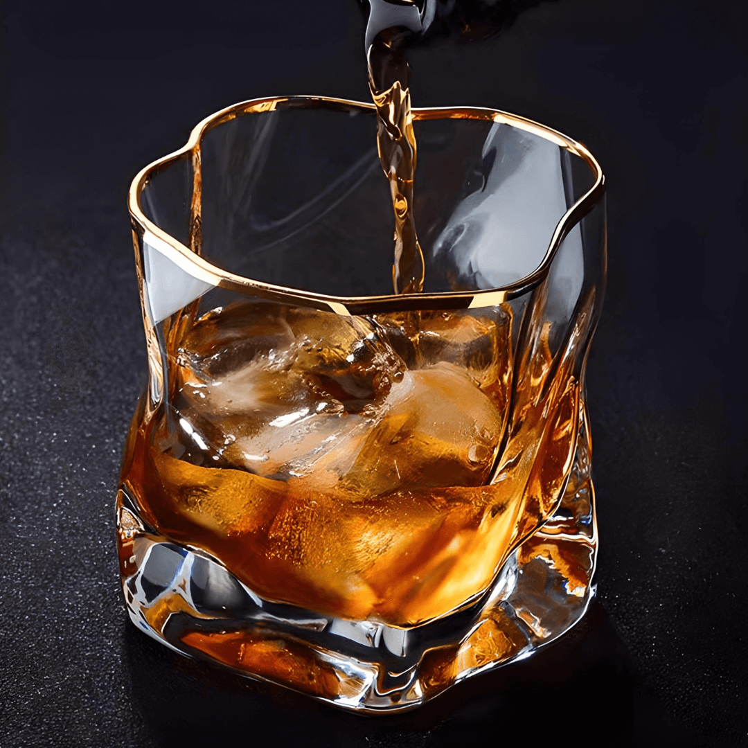 Gold Hoshi Japanese crystal whisky glass with gold rim and textured grip, whisky swirling with ice.
