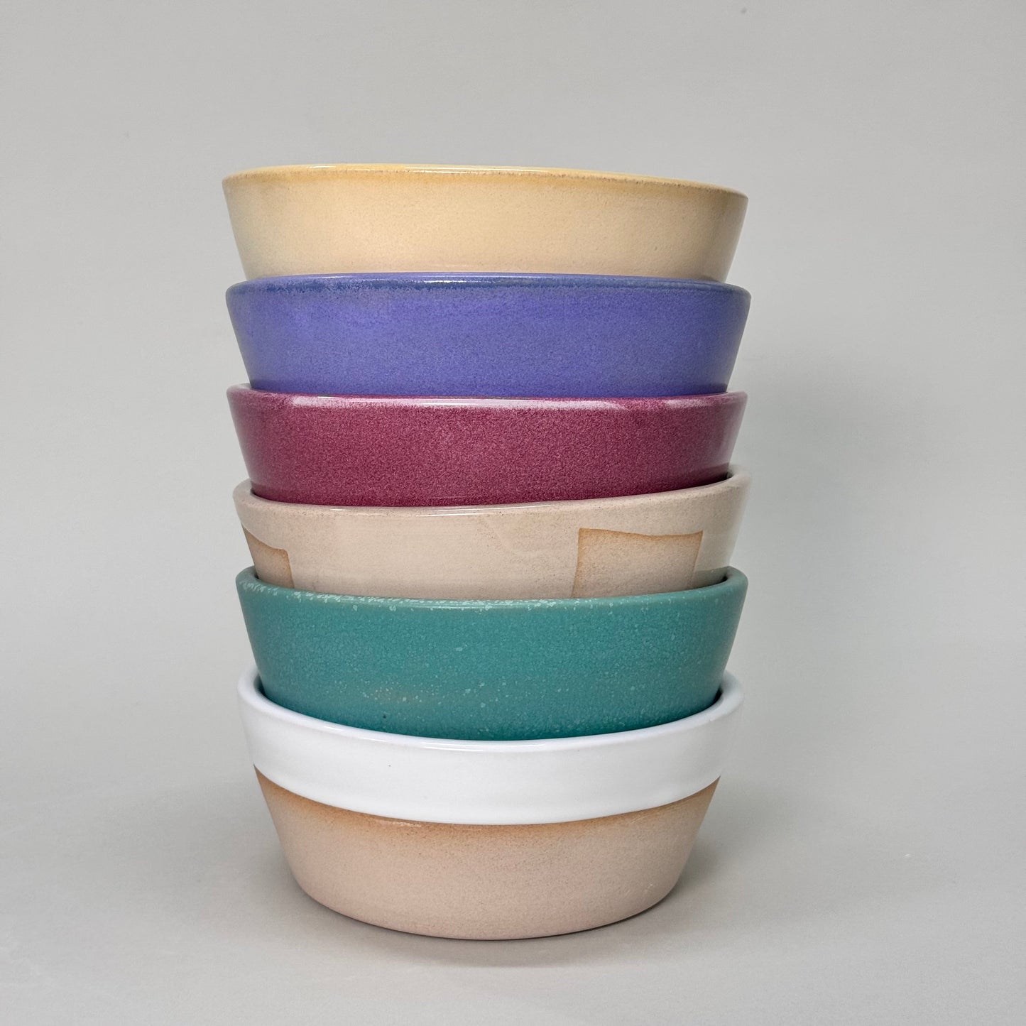 Stack of The Standard Soup Bowl 6-inch ceramic bowls in pastel colors, ideal for soups, salads, or cereal.