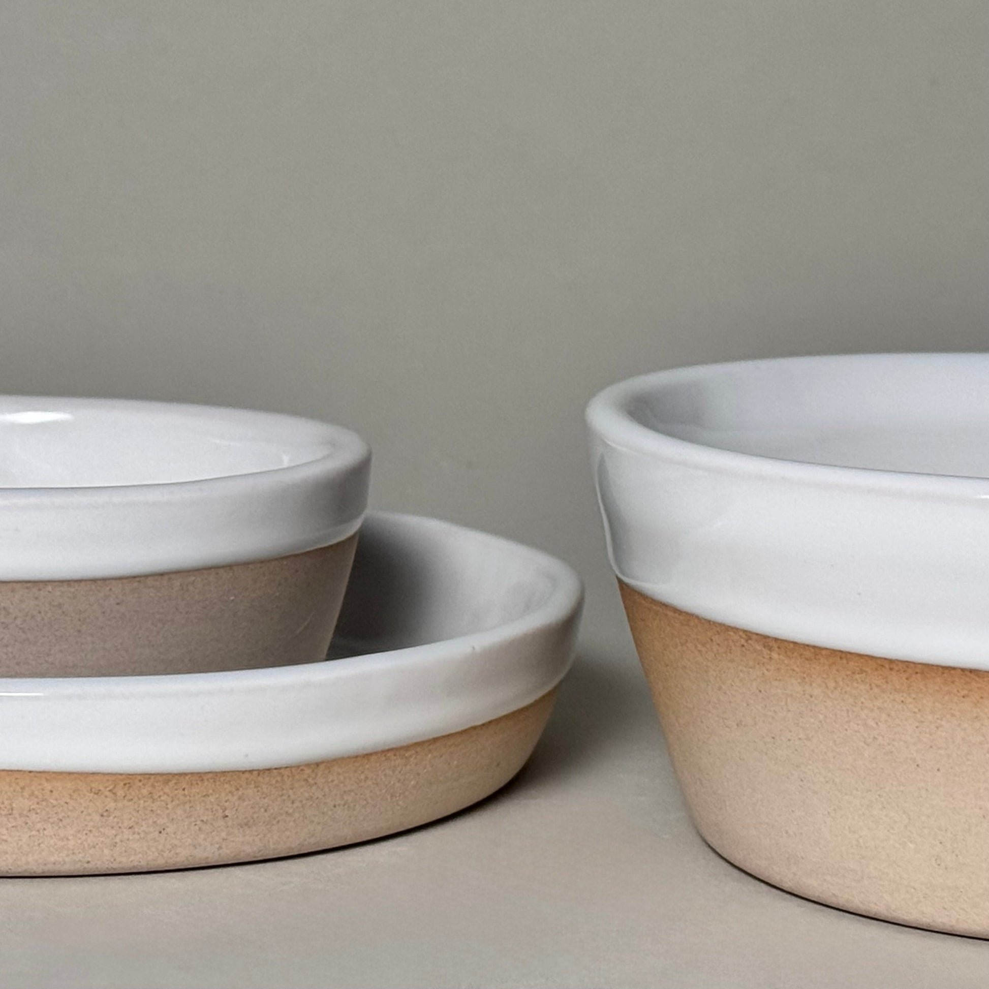 Two 9-inch share bowls with white-glazed rims and natural tan bases, wide shallow design.