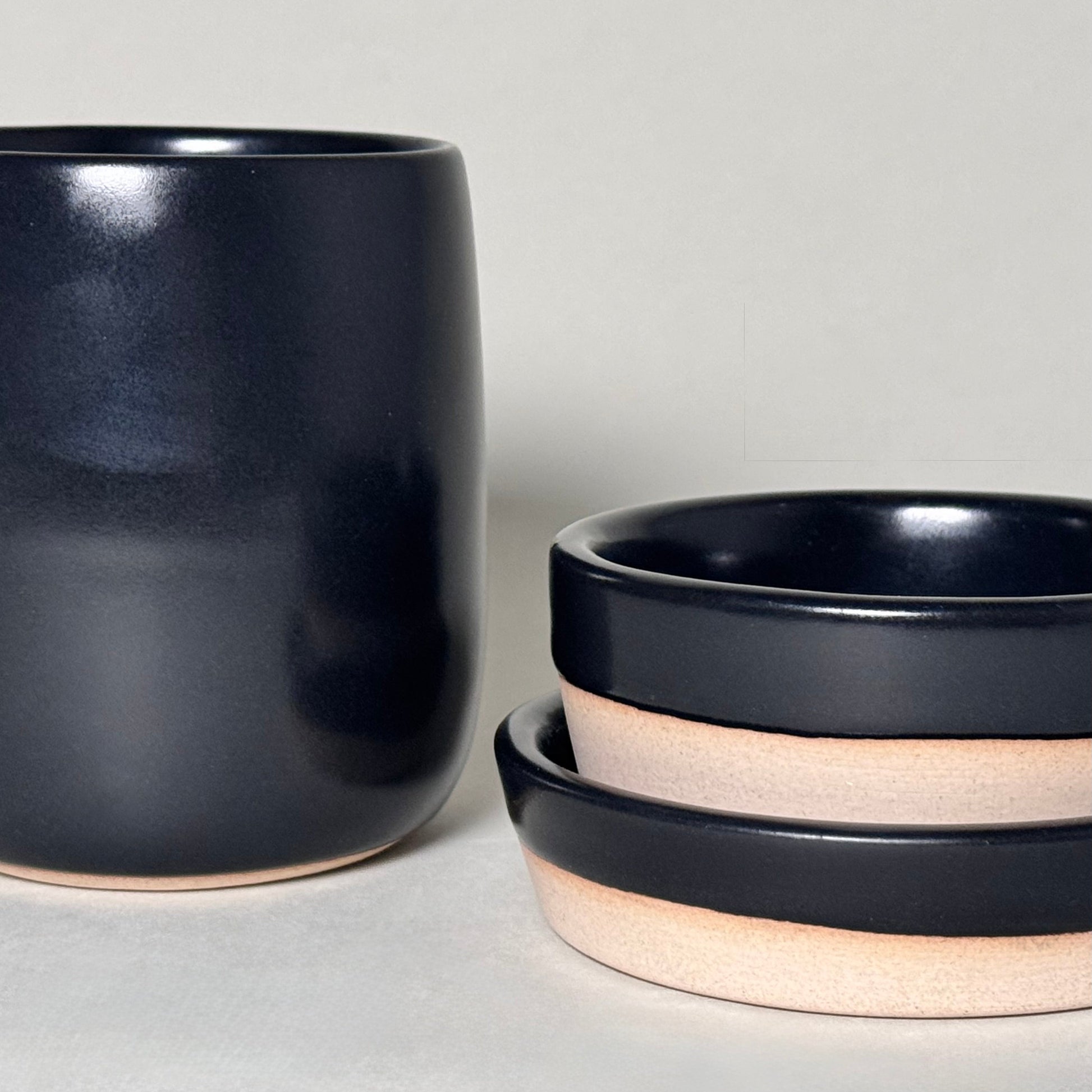 Share Bowl 9-inch ceramic bowls with wide opening and beige unglazed rims, stacked beside a tall vase.