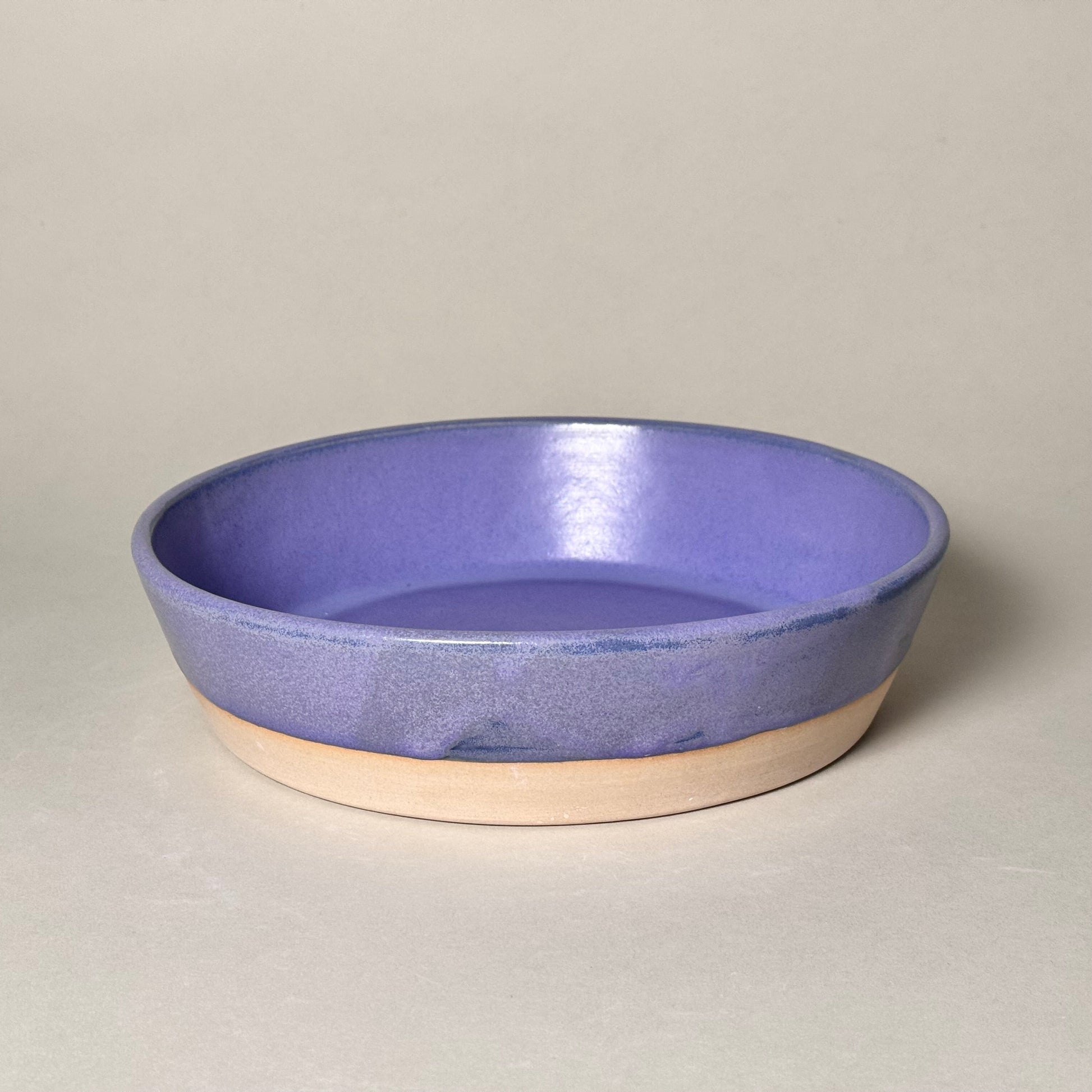 Share Bowl 9-inch ceramic bowl with purple glaze and beige base.