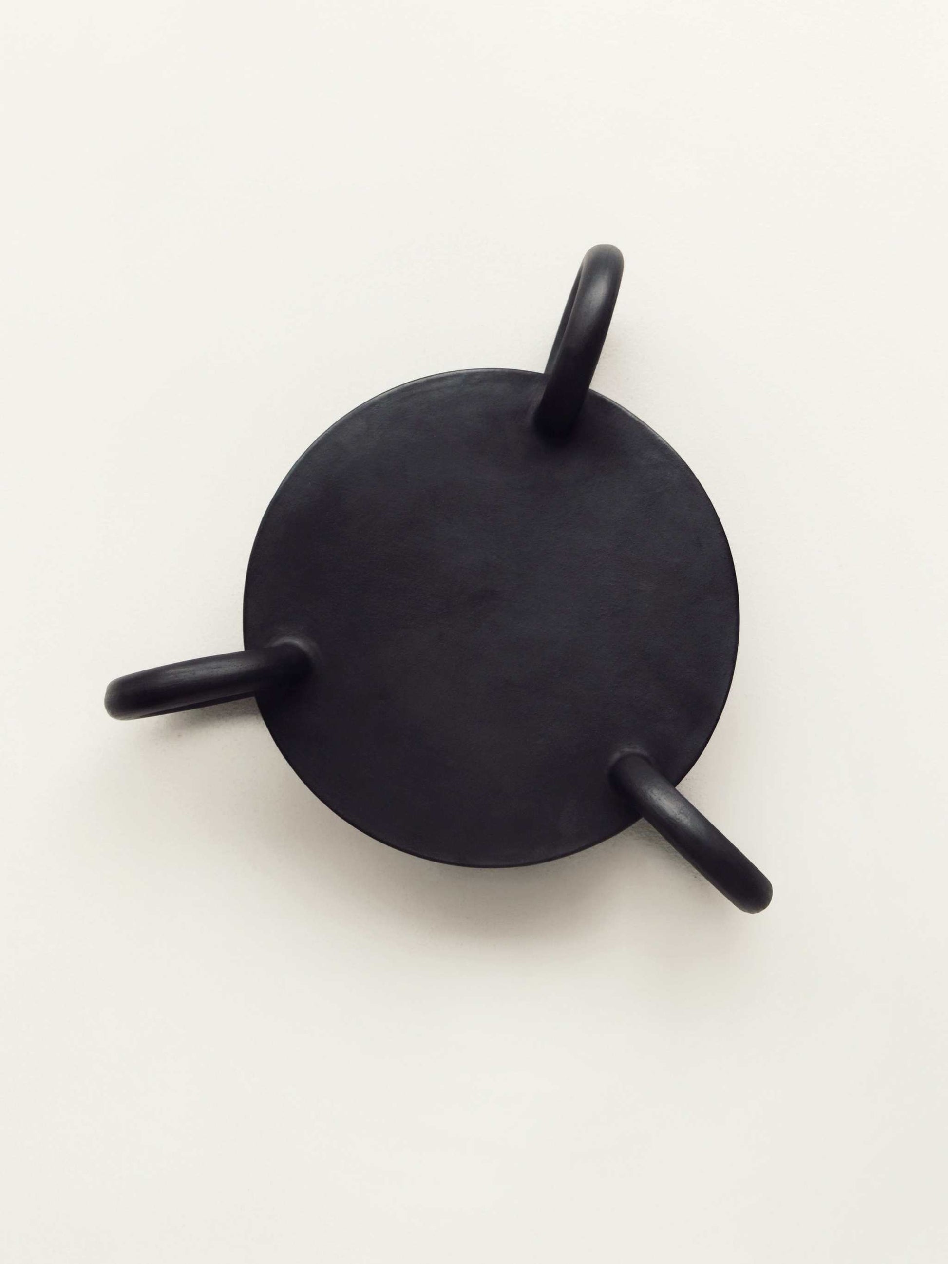 Large round Guculia Trinity serving platter with three handles in matte black.