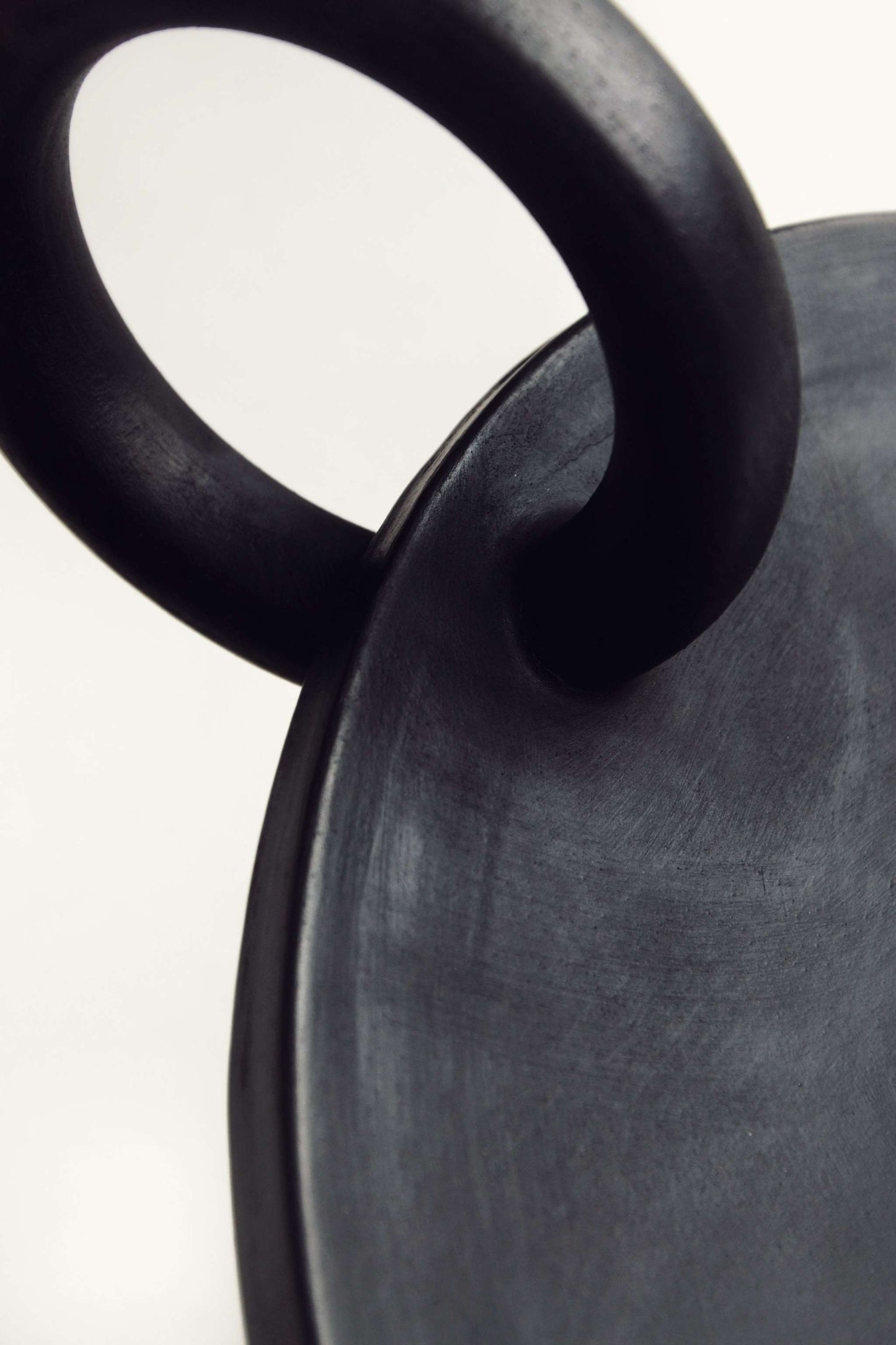 Close-up of the black Large Serving Platter Guculia Trinity with a curved ring handle.