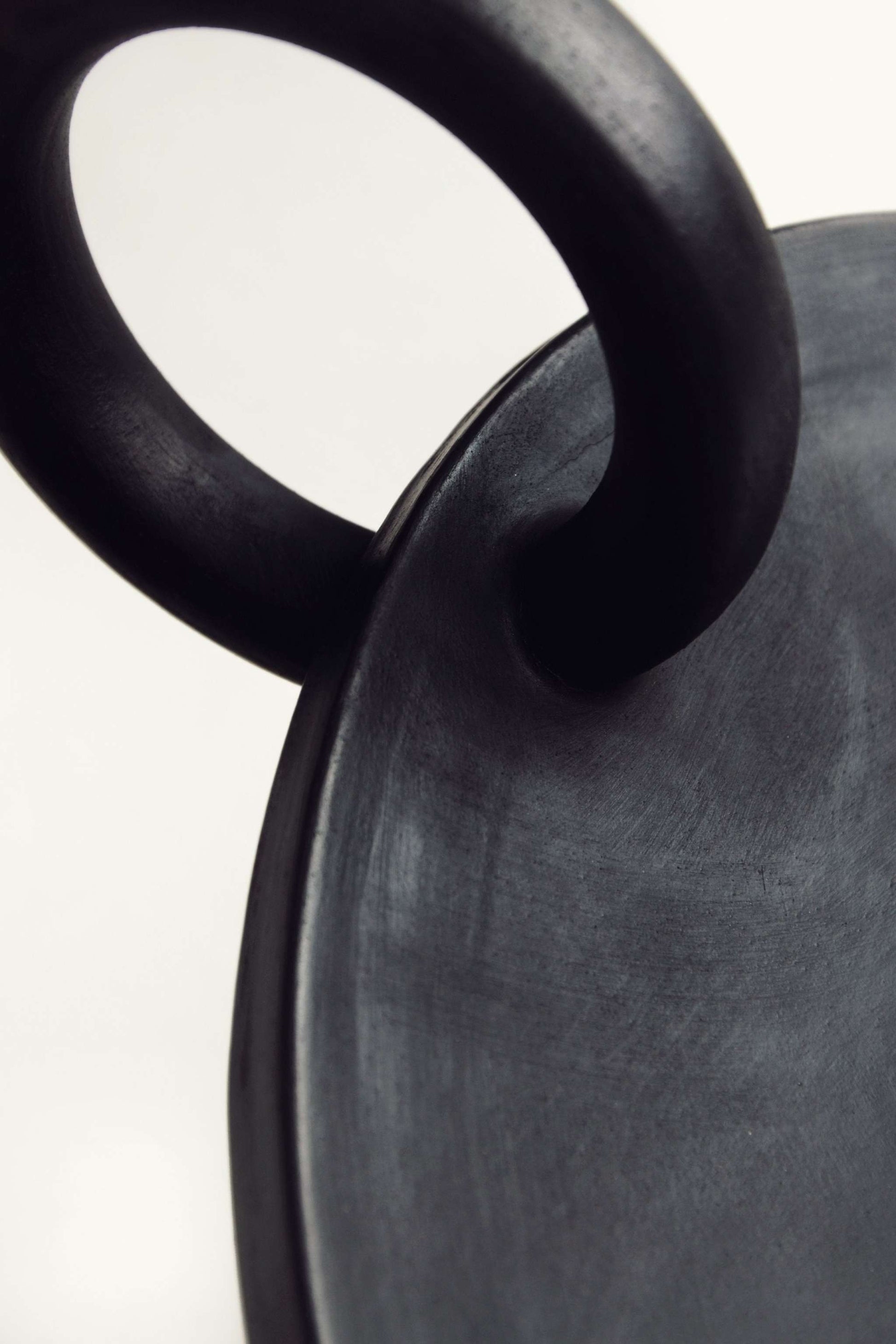 Close-up of the black Large Serving Platter Guculia Trinity with a curved ring handle.