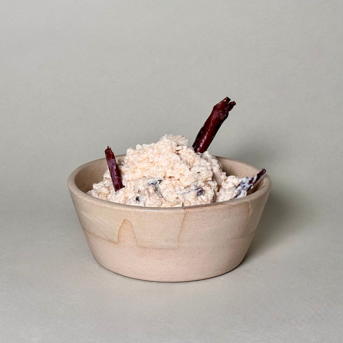 6-inch ceramic soup bowl filled with a creamy dish and two cinnamon sticks.