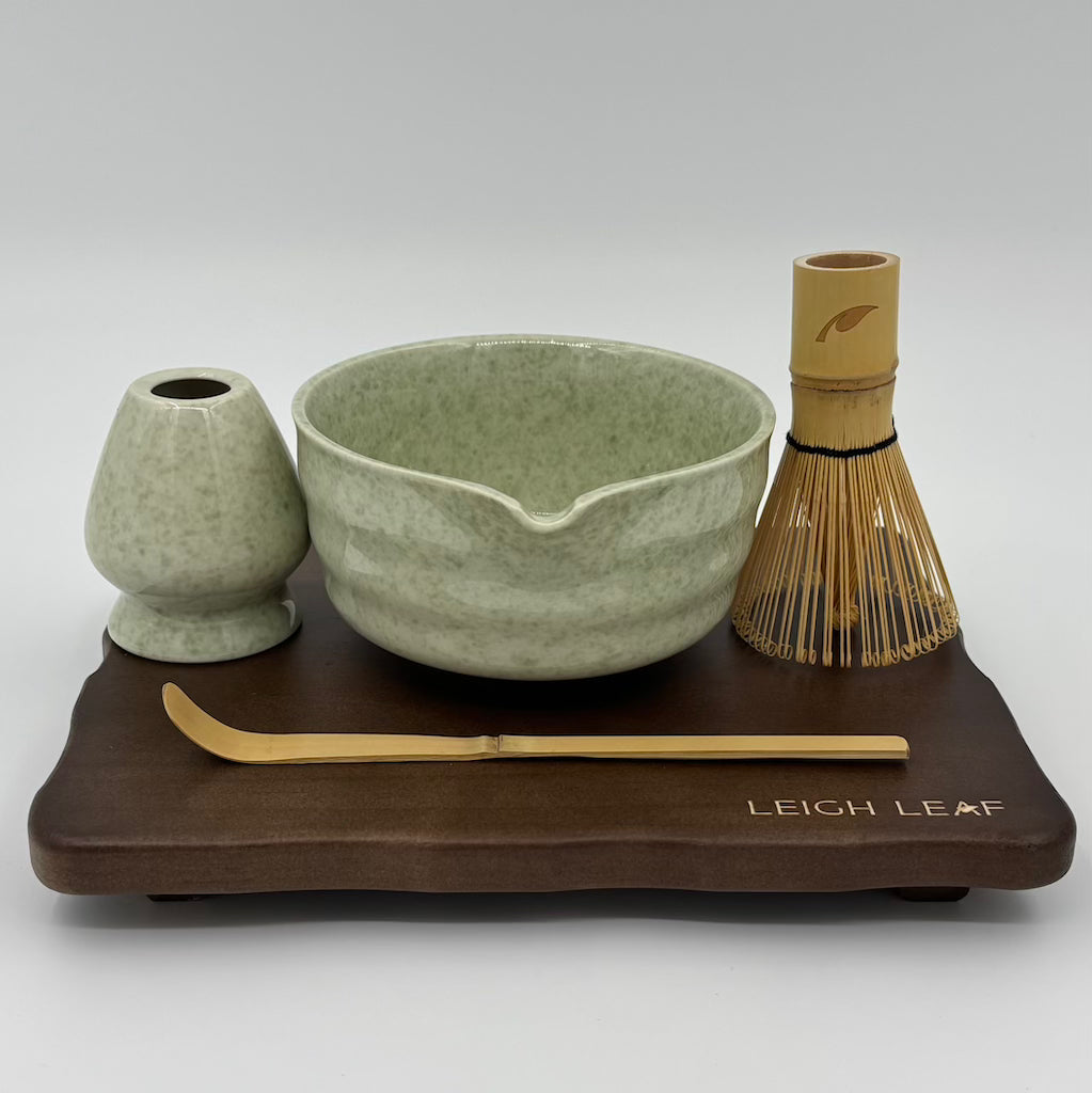 5 Piece Matcha Whisk Set on a wooden display board with Leigh Leaf bamboo whisk, green ceramic bowl, and chashaku