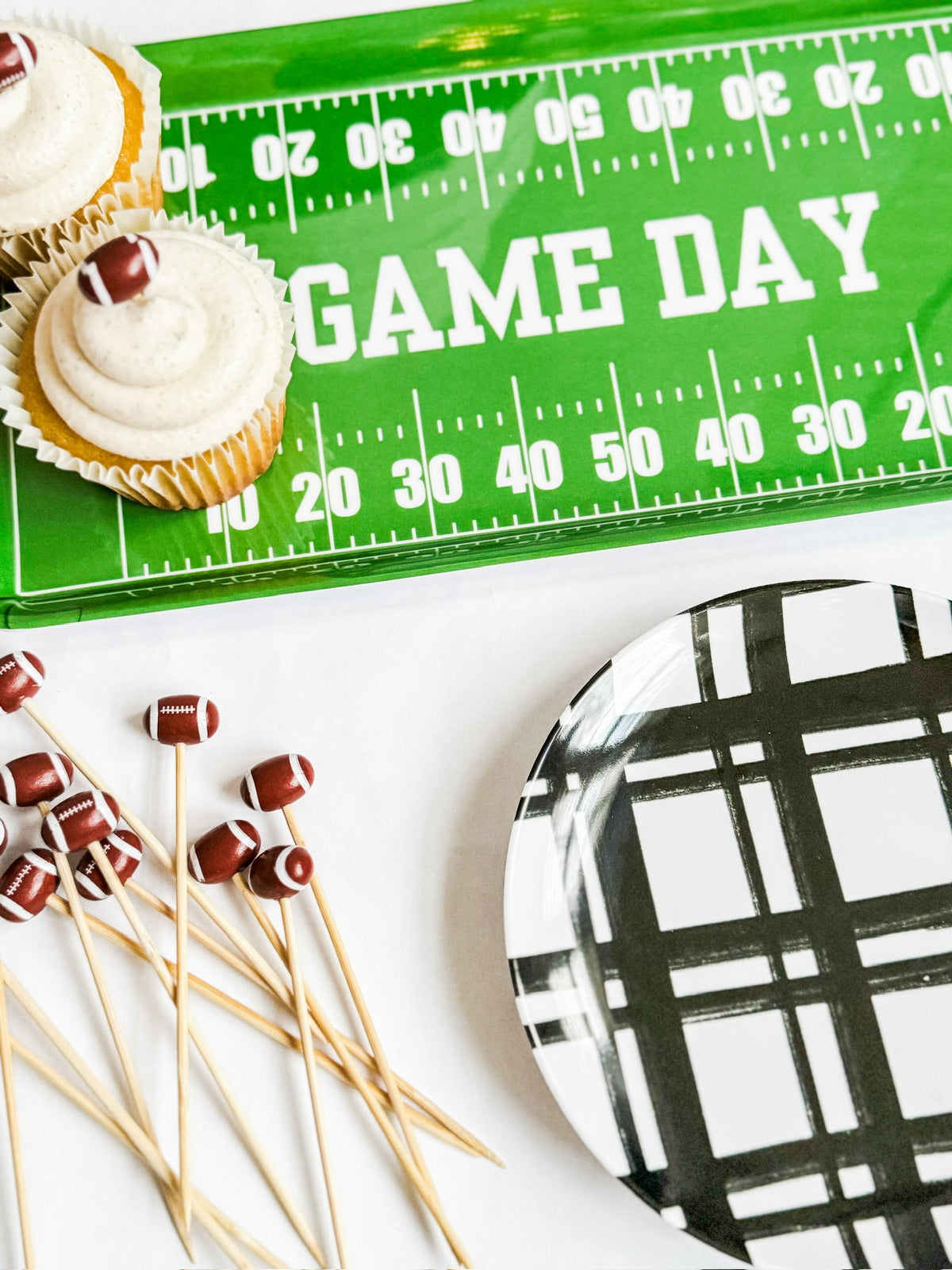 Green football field melamine tray with GAME DAY text, holding cupcakes and football skewers for tailgate parties.