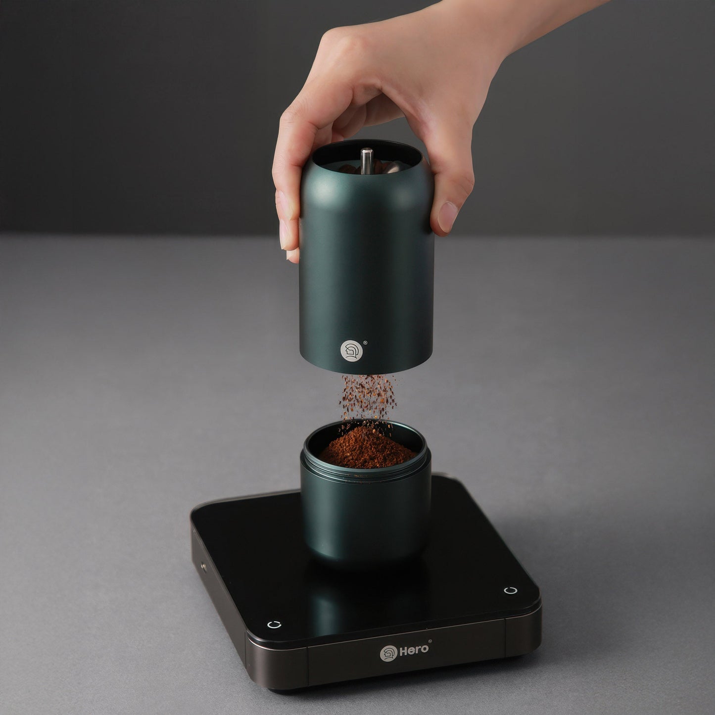 Dark green Z7 manual coffee grinder for pour-over over a scale as ground coffee falls into the lower chamber.