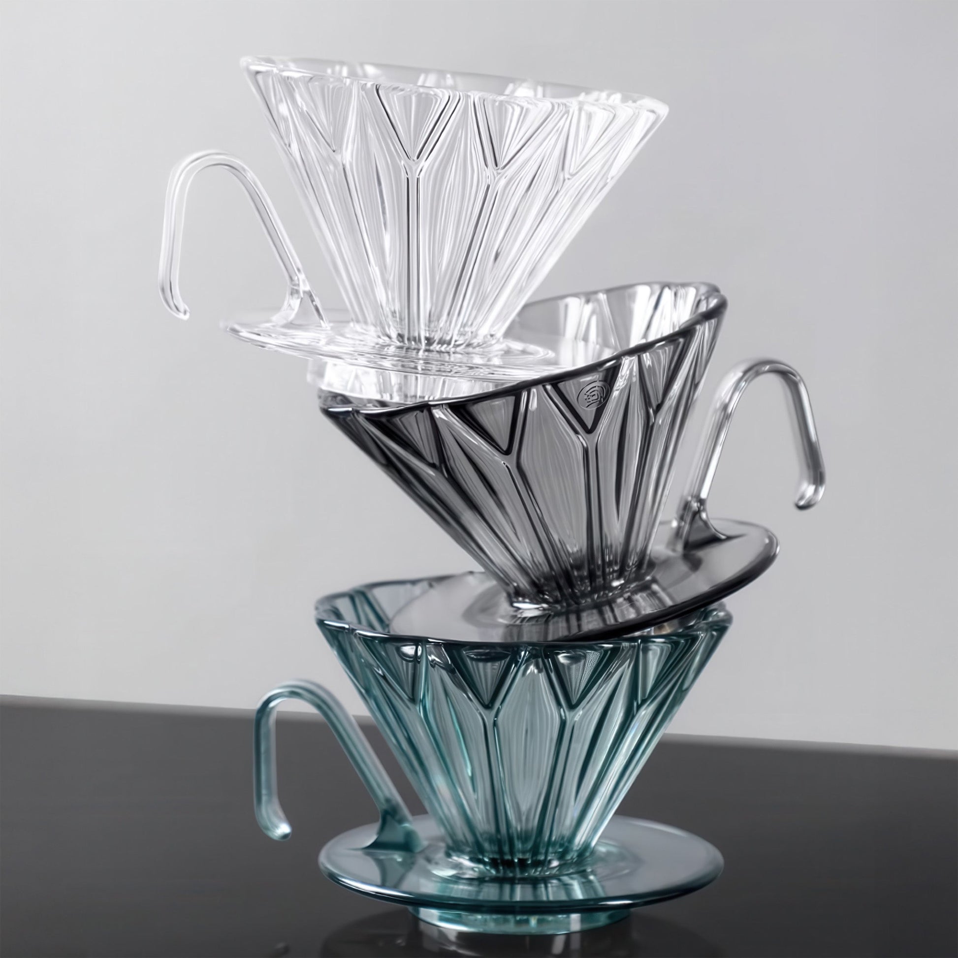 Diamond Pattern Prisma Pour Over Coffee Drippers in clear, smoky gray, and teal, stacked with handles.