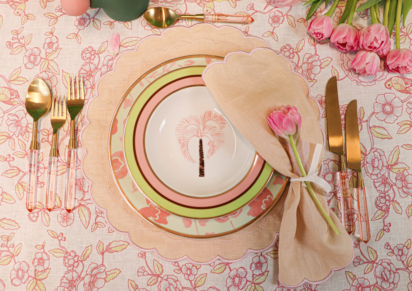 Peony Blush gold-toned cutlery with rose-petal handles beside pastel plates and pink roses on a floral table setting.