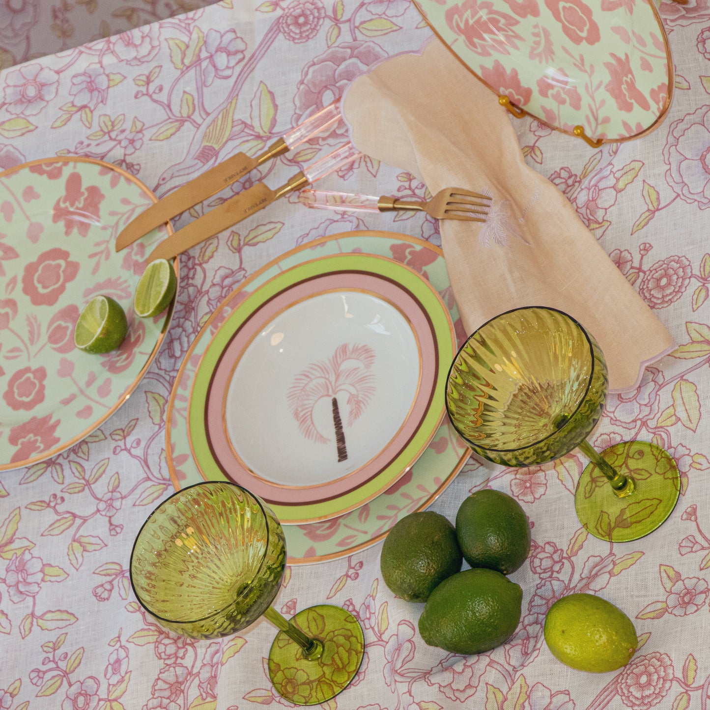 24pc Peony Blush Cutlery set with gold-toned handles and rose-petal details, pastel plates, and green glassware.