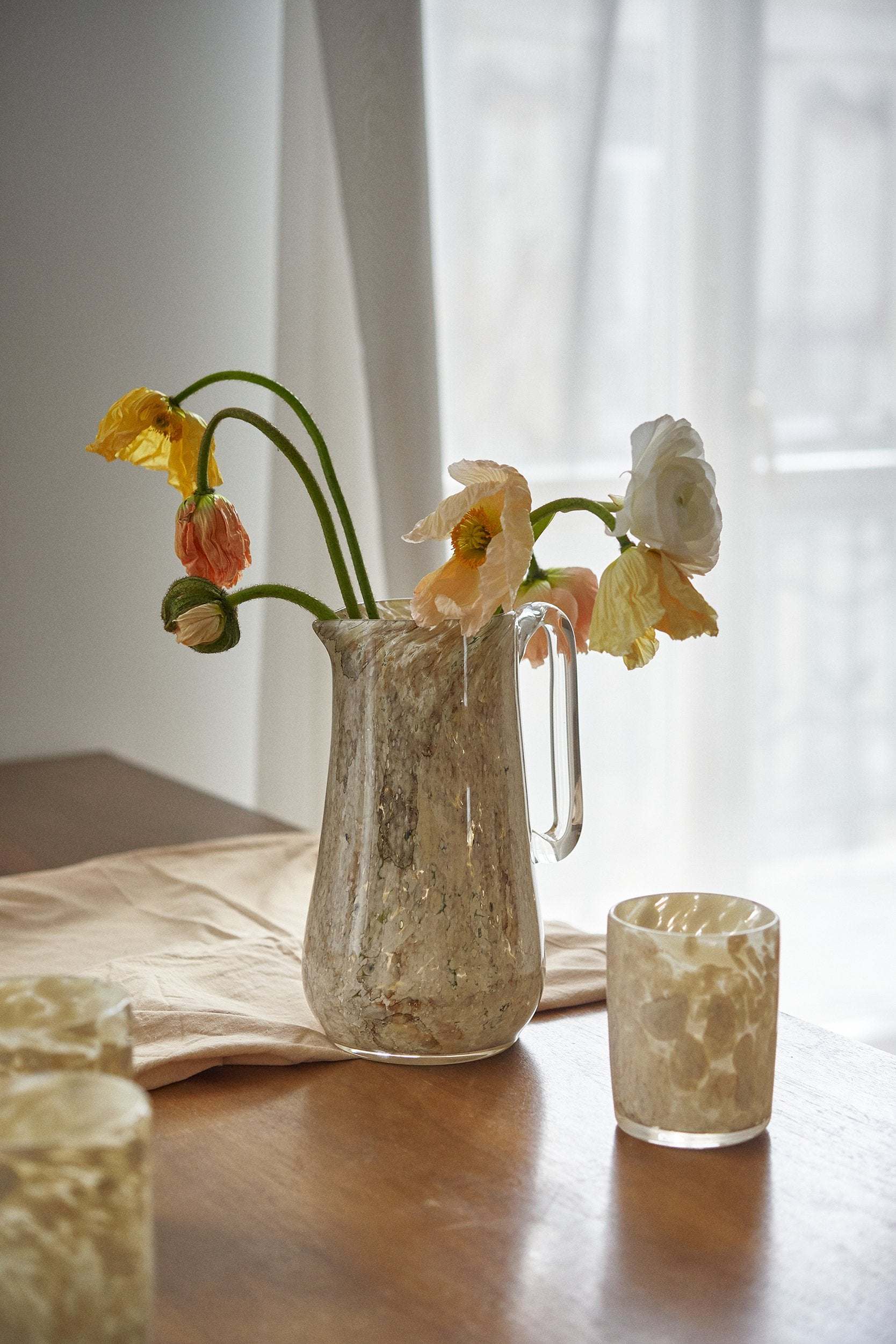Hand blown glass pitcher with marble-inspired pattern and sturdy handle, used to display water, drinks or flowers