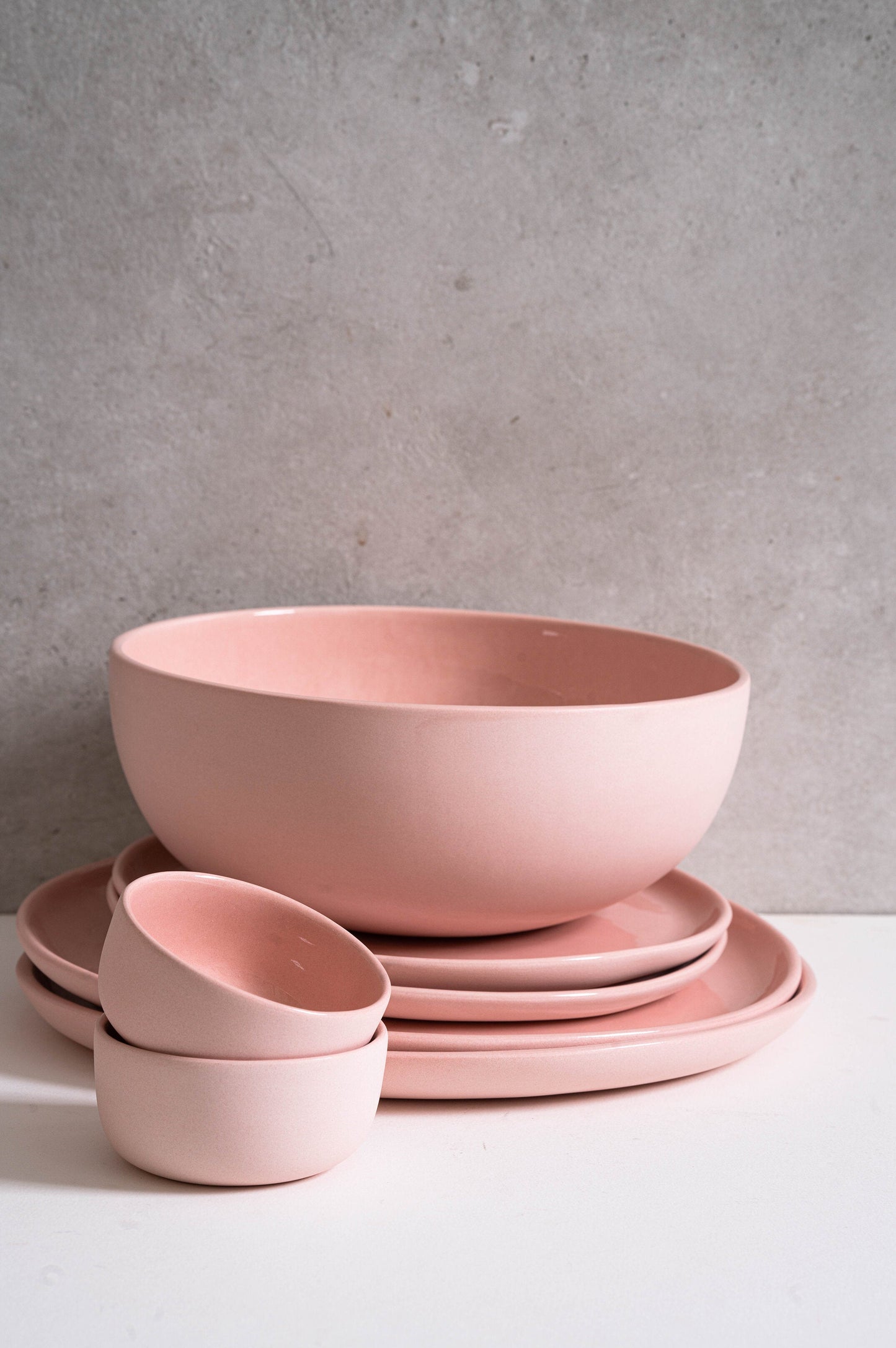 Powder pink handmade porcelain salad serving bowl with coordinating plates and small bowls.