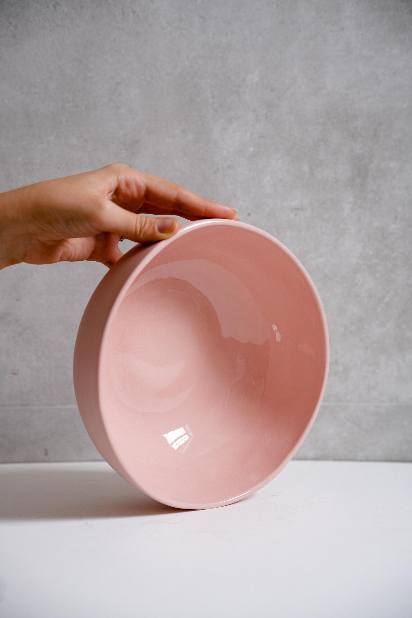 Powder pink handmade porcelain salad serving bowl held in hand.