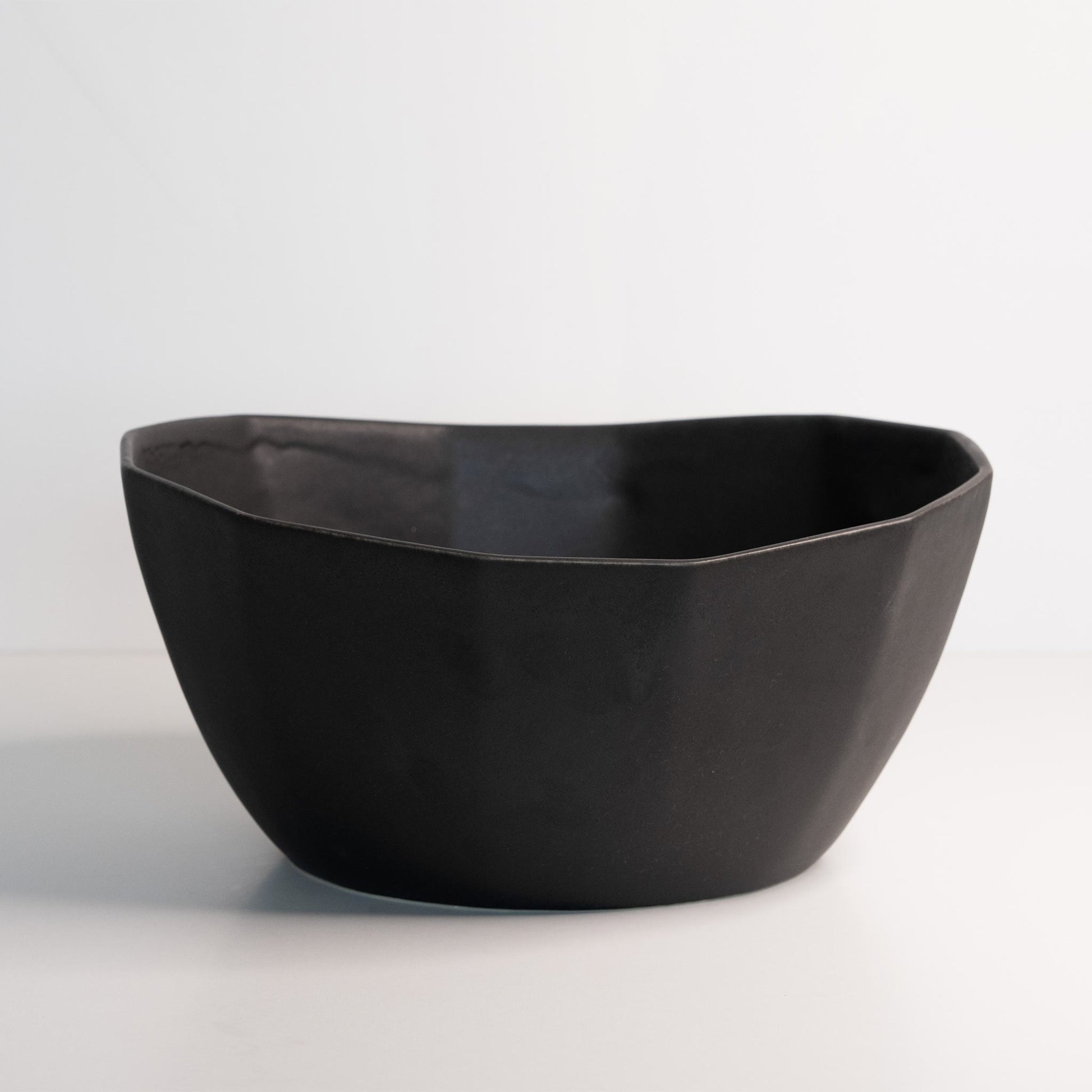 Large porcelain nesting bowl in matte black, handmade ceramic, ideal for pasta or salads.