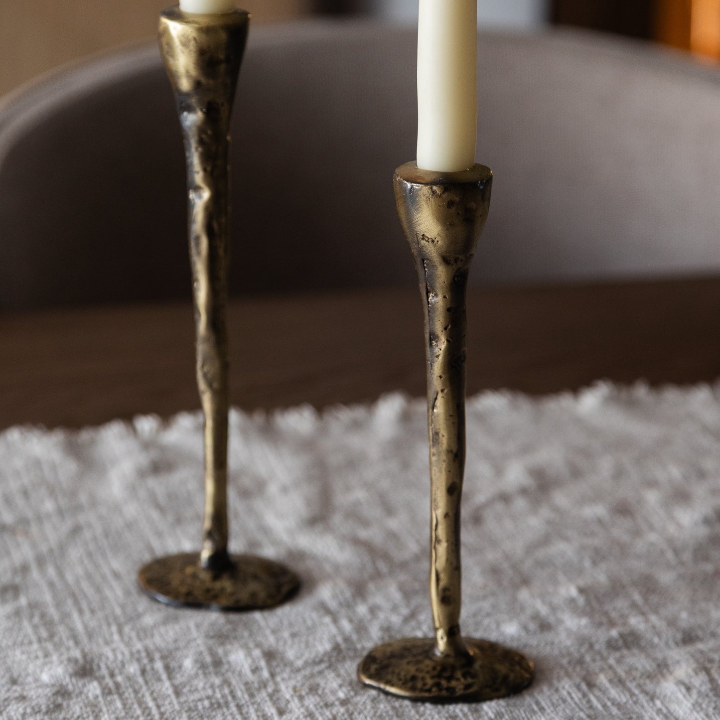 Two of three antique brass large candlesticks, hand-forged in northern Greece, Byzantine-inspired, on linen.