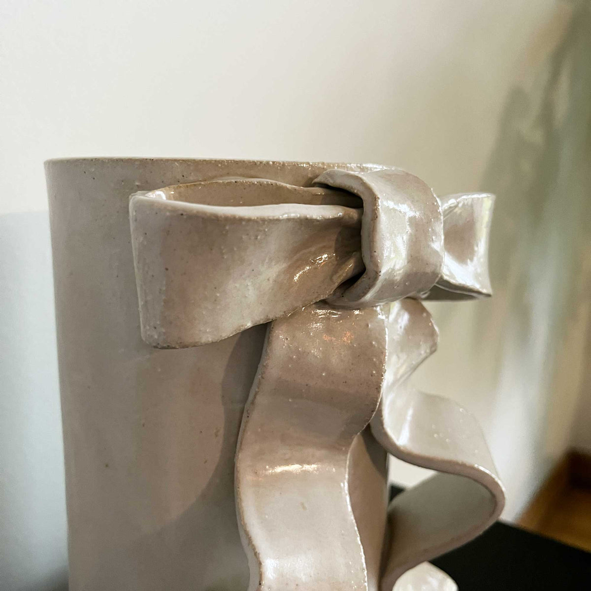 Handmade satin white glazed stoneware vase featuring a sculpted ribbon bow for a whimsical touch.