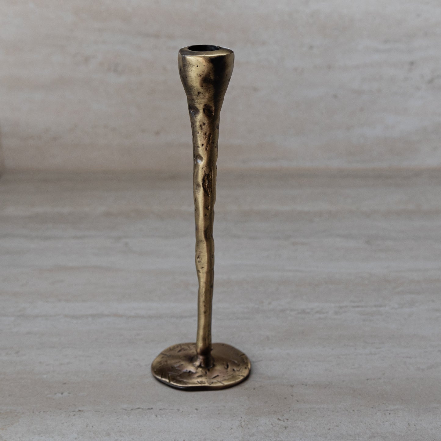 Tall antique brass candlestick, hand-forged with hammered texture and round base.