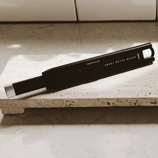 Black large rechargeable electric lighter with ergonomic grip resting on a beige stone countertop.