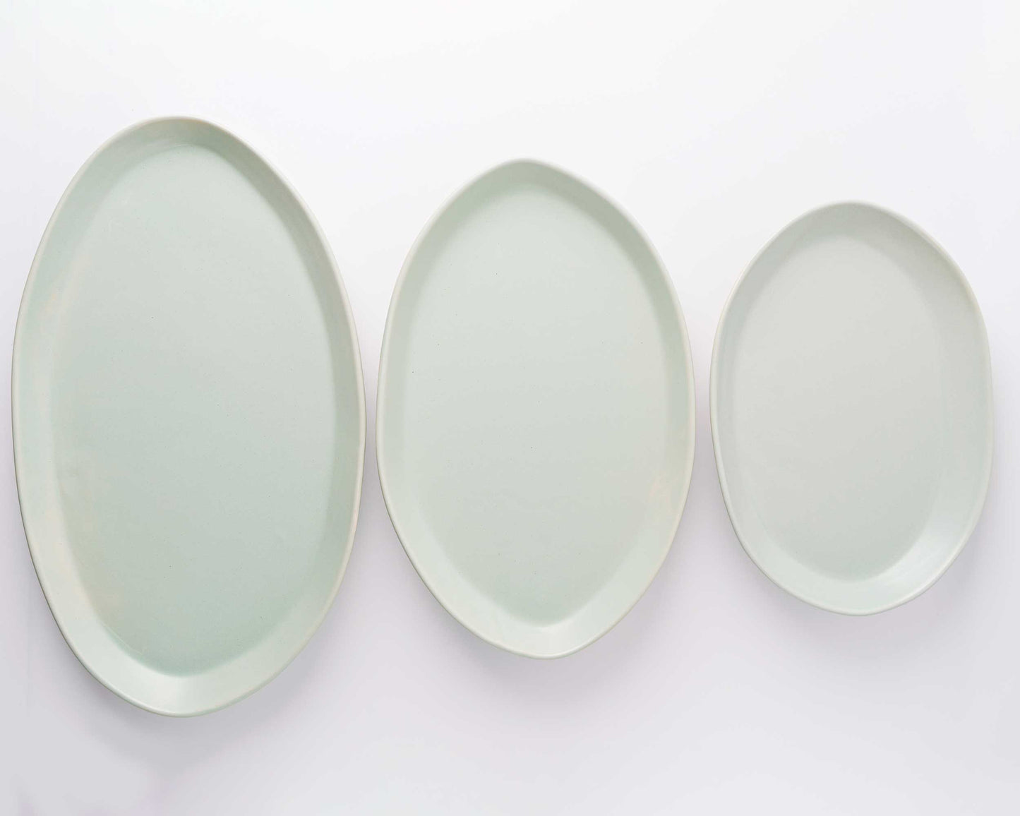 Three oval serving platters in pale green glaze, sizes 13 in, 15 in, and 18 in.