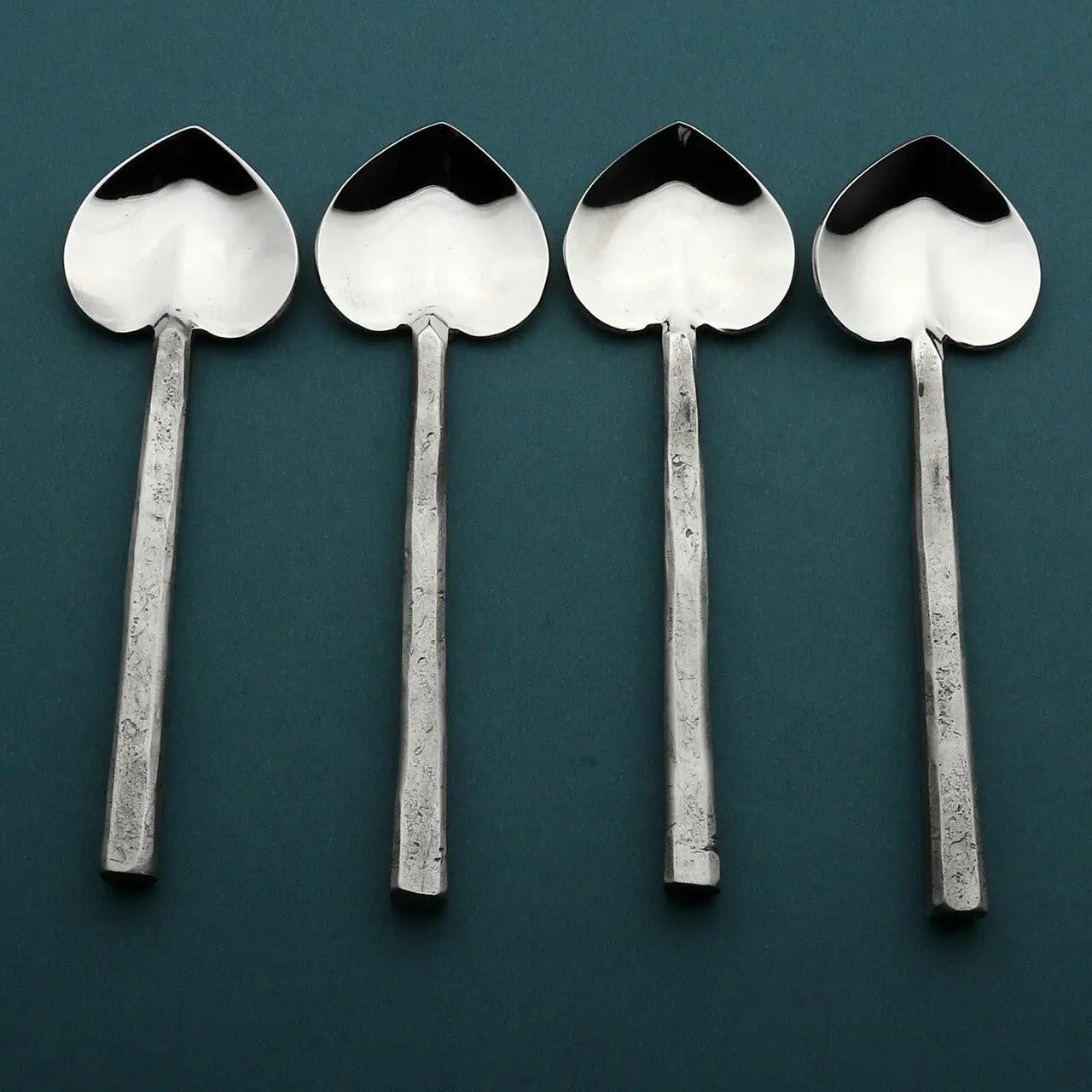 Four Jason Heart coffee/dessert table spoons with heart-shaped bowls and square handles on teal background.