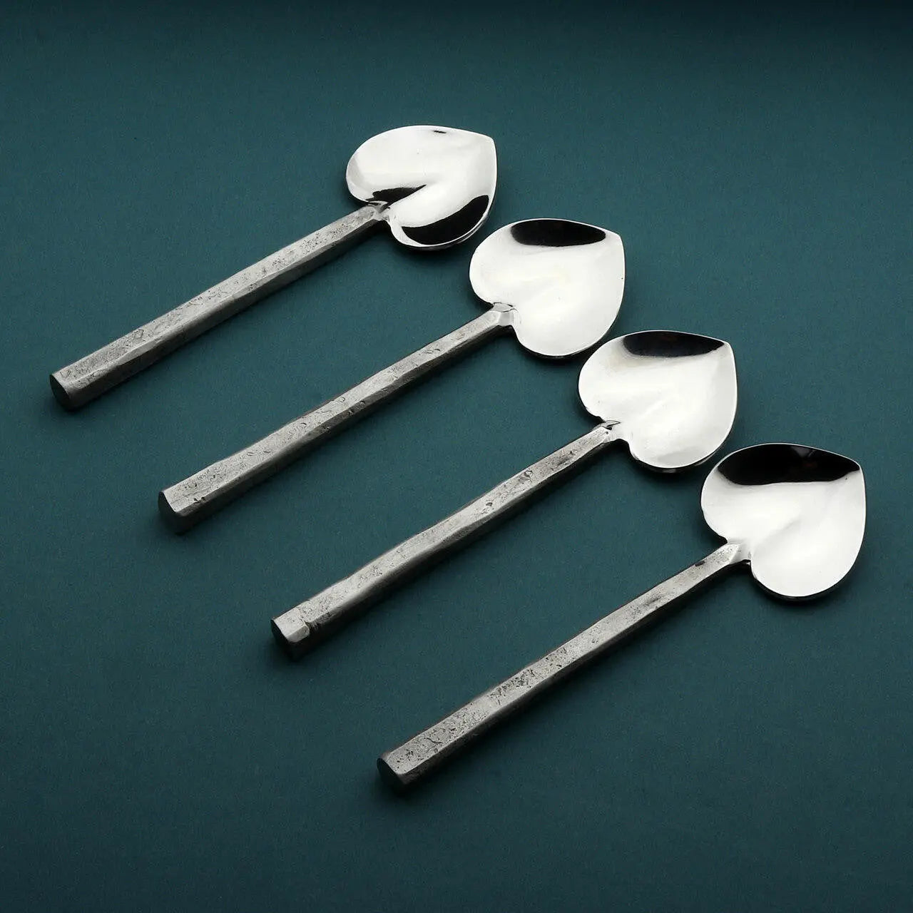 Jason Heart four-piece coffee/dessert spoon set with heart-shaped bowls and square hammered handles on teal background.