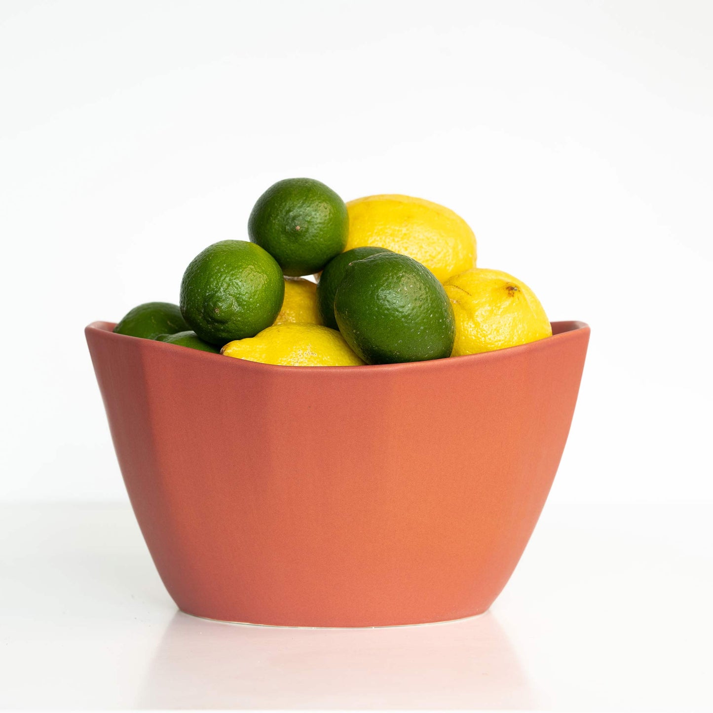 Medium Porcelain Nesting Bowl by Ember Collective filled with lemons and limes.