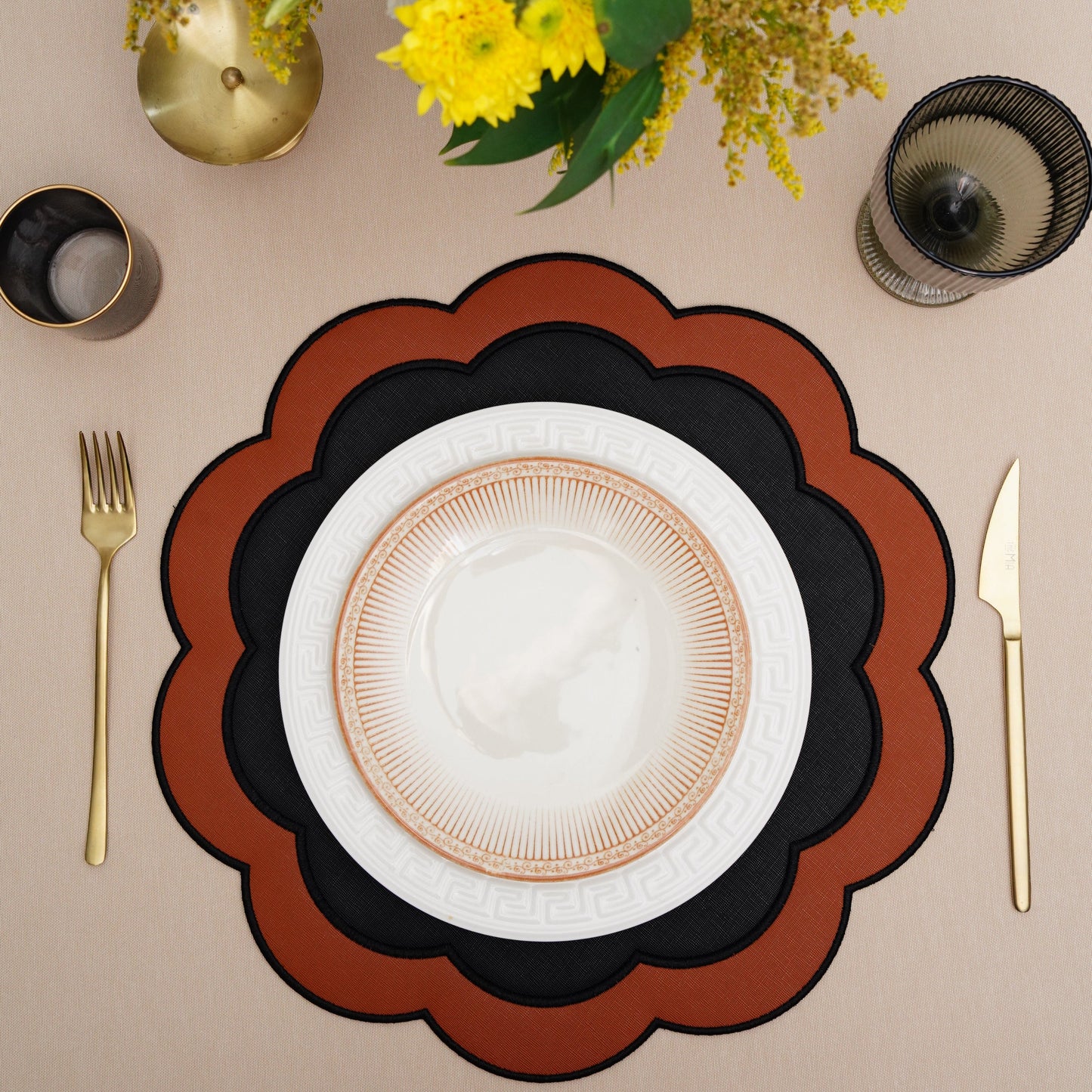 Serenity black-orange scalloped faux leather placemat with white plate and gold flatware.