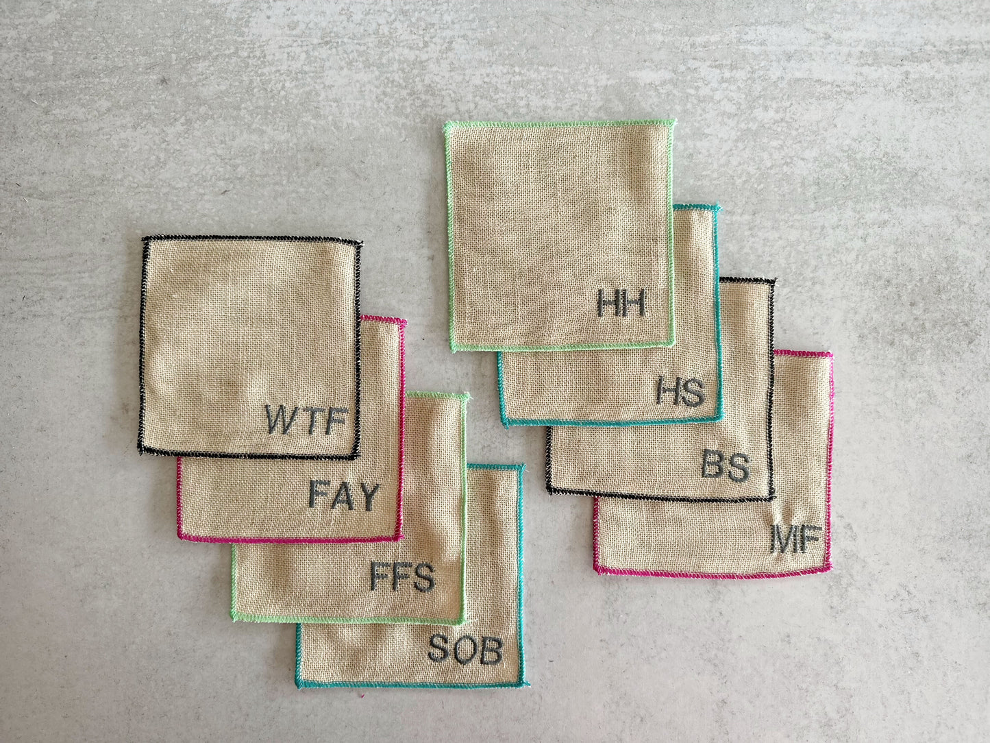 Colorful-edged burlap cocktail coasters, 8-piece set with embroidered initials that spell swear words.