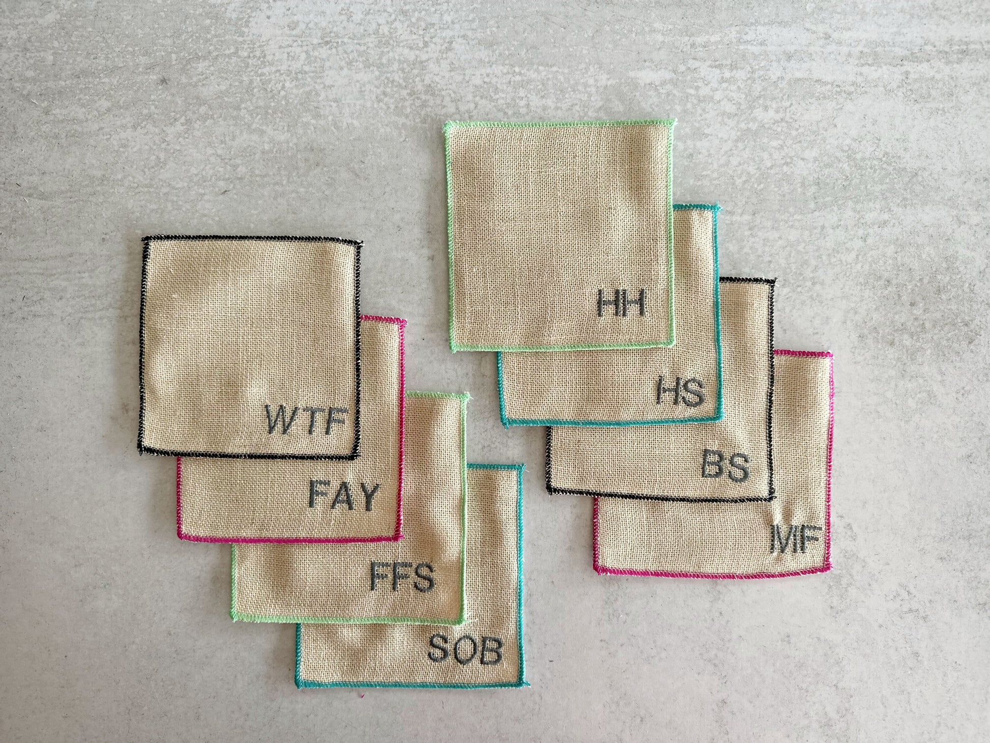 Colorful-edged burlap cocktail coasters, 8-piece set with embroidered initials that spell swear words.